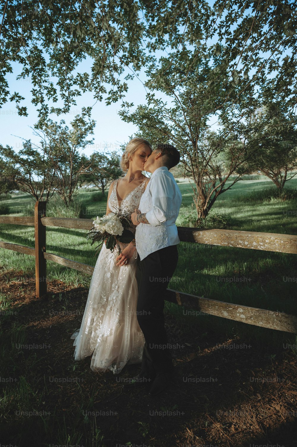 Una sposa e uno sposo che si baciano davanti a una recinzione