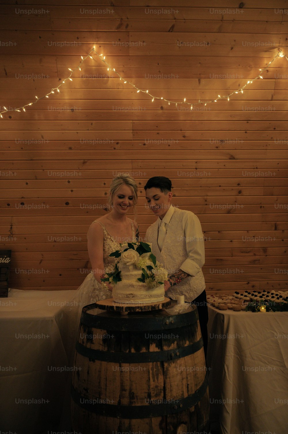 a man and woman standing next to a barrel with a cake on it