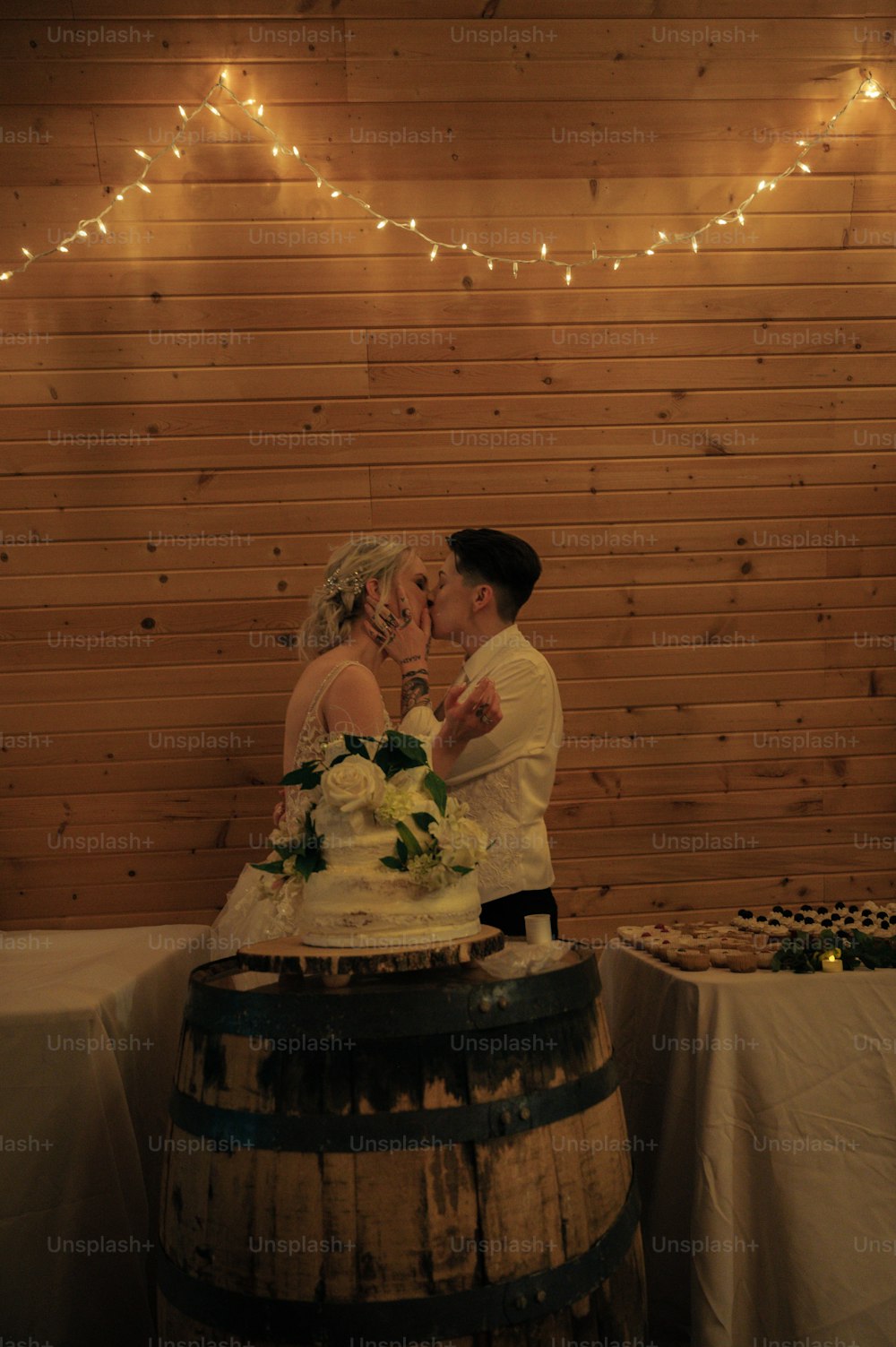 a bride and groom kissing in front of a cake