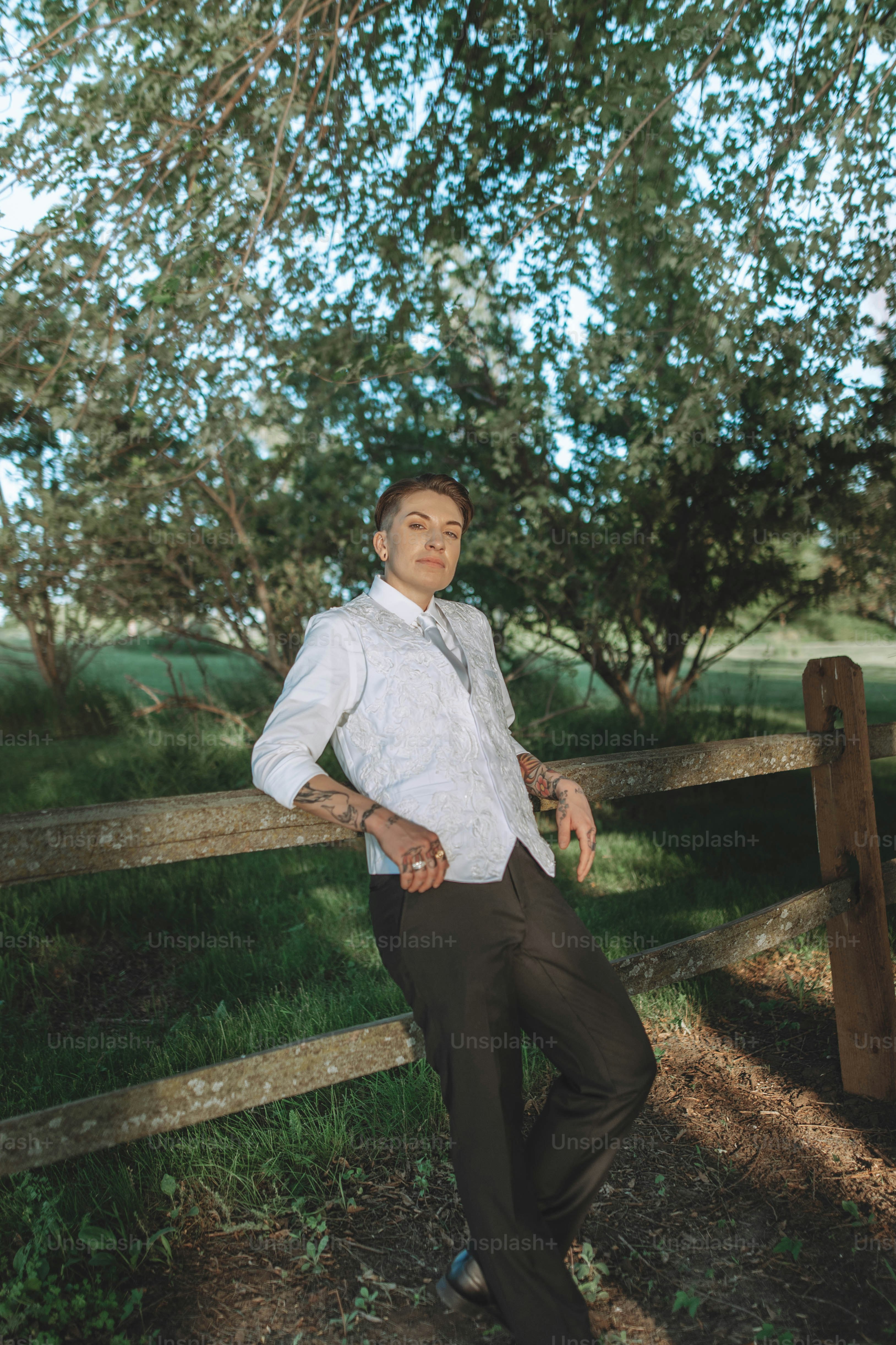 a man leaning on a wooden fence in a field