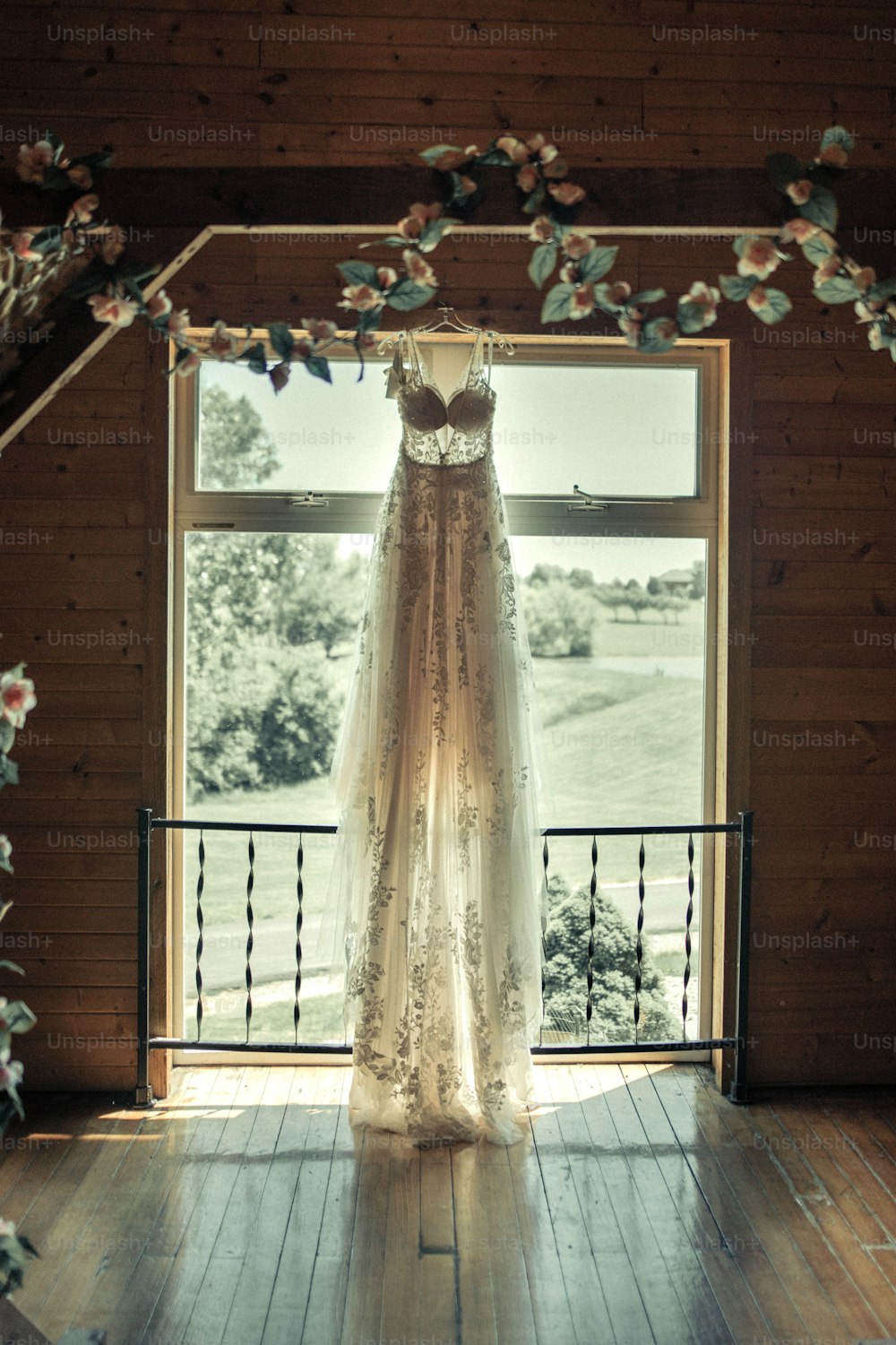 a wedding dress hanging in front of a window
