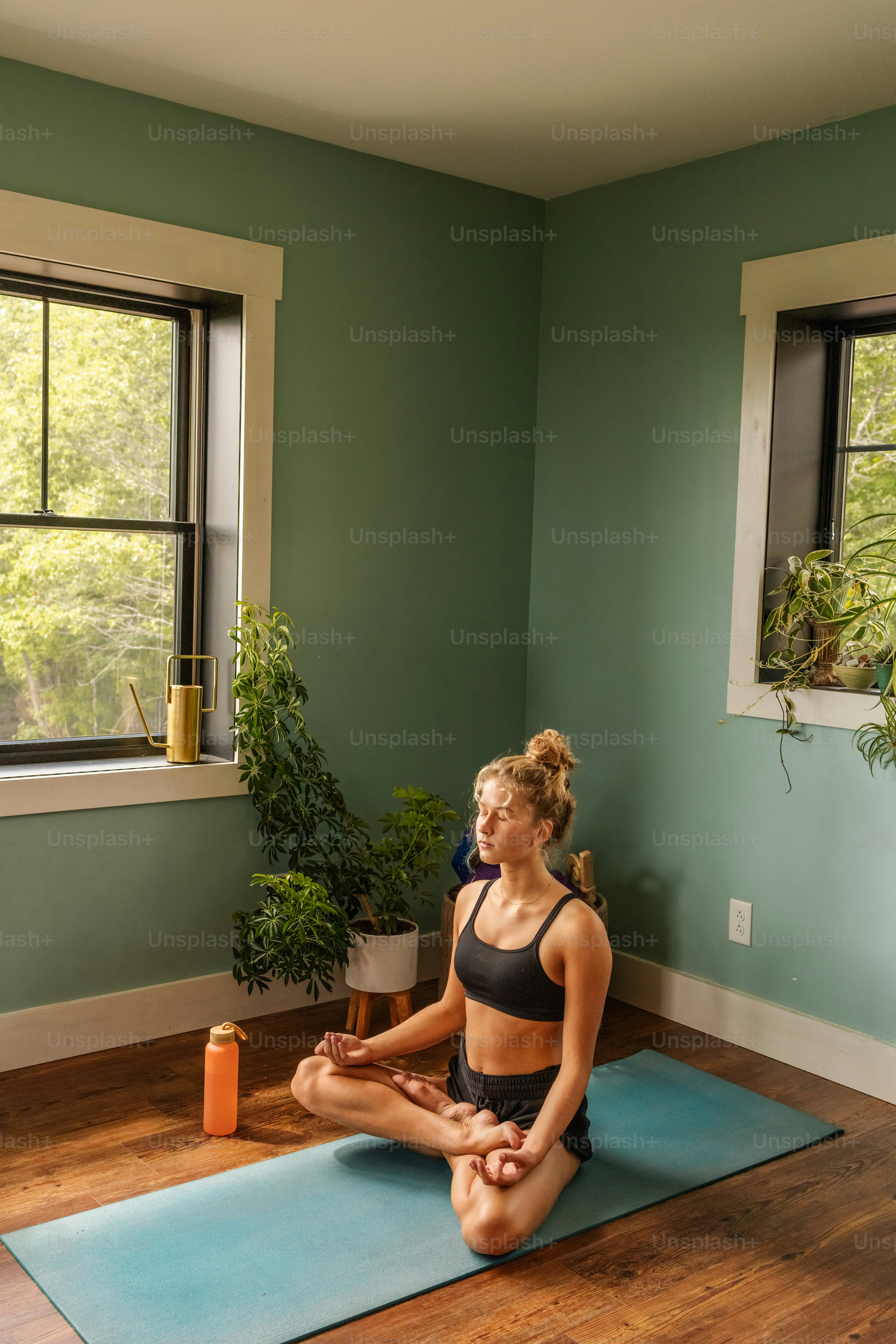 eine frau, die auf einer yogamatte in einem raum sitzt
