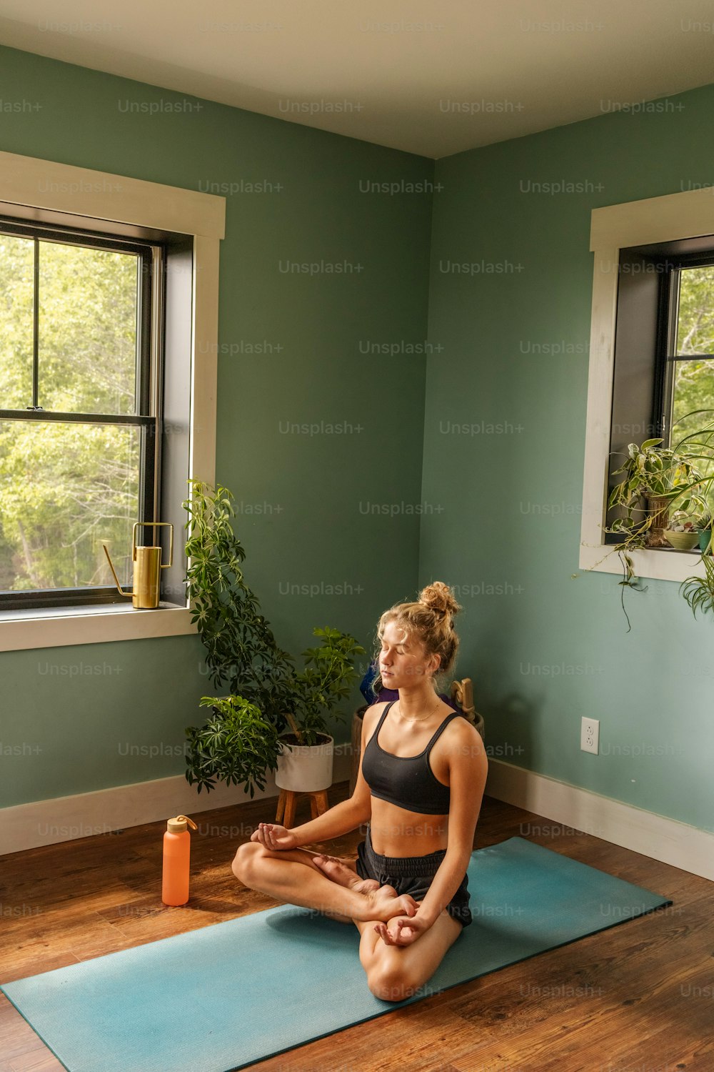 a woman sitting on a yoga mat in a room