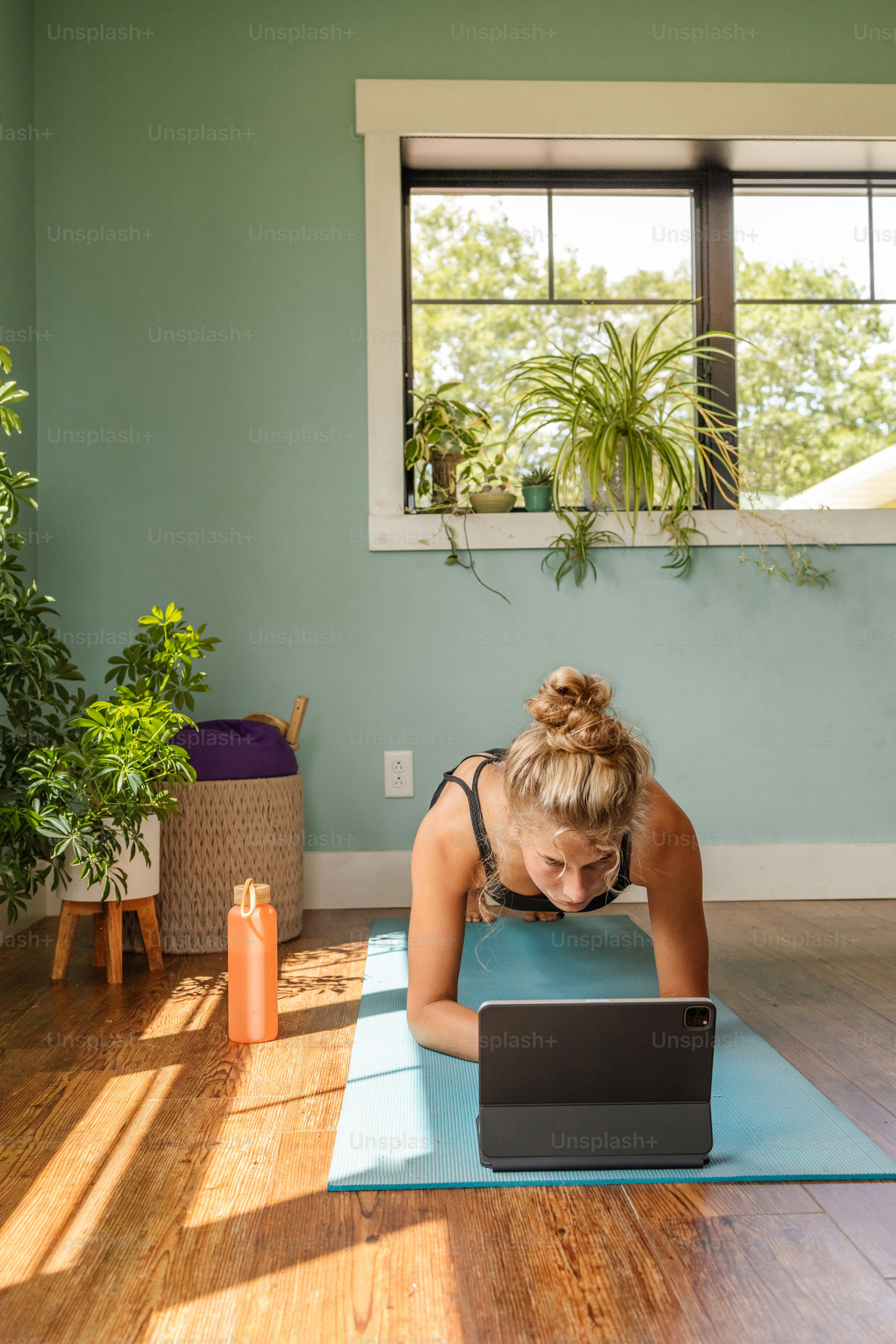 une femme sur un tapis de yoga utilisant un ordinateur portable