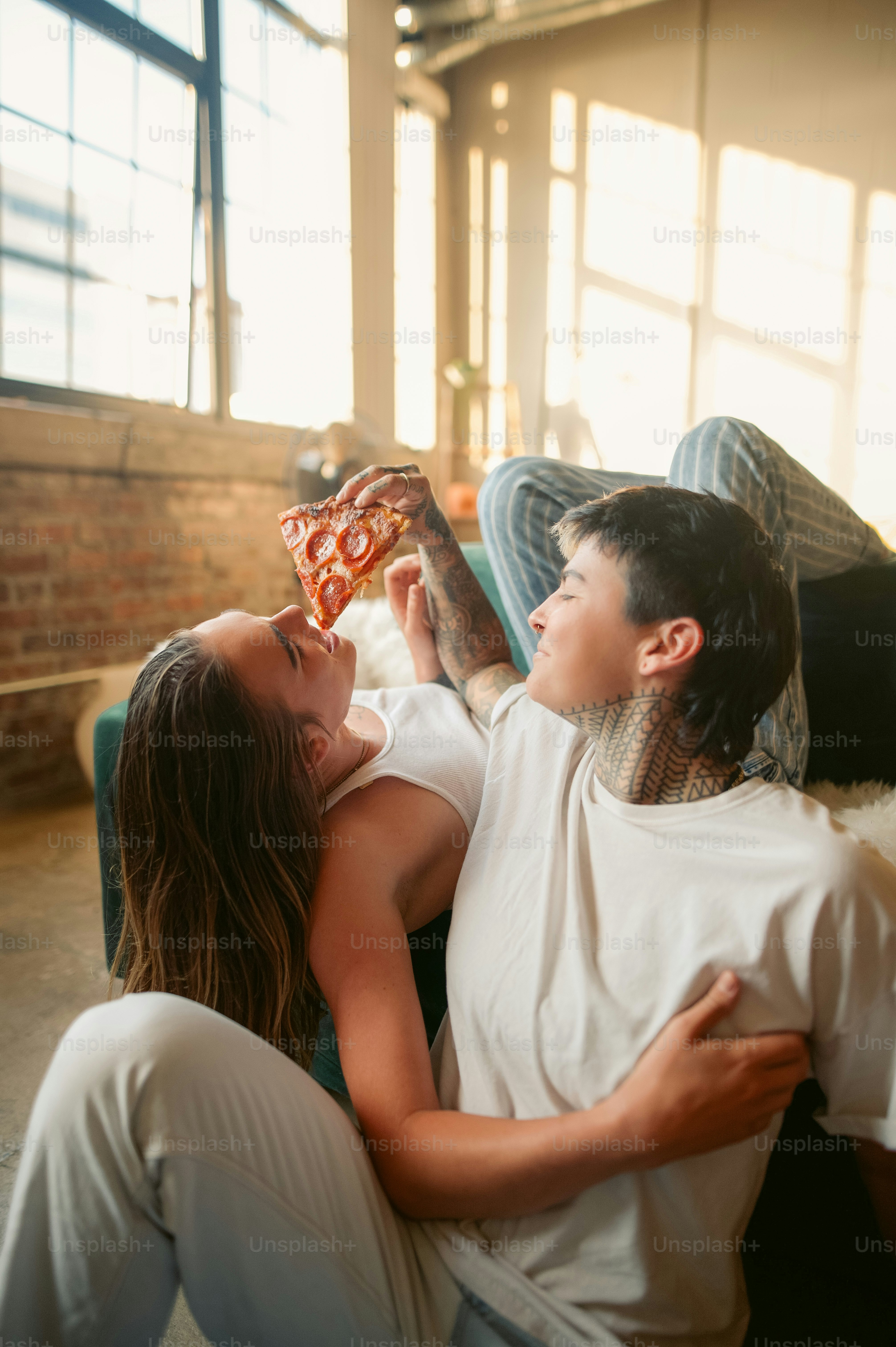 Un uomo e una donna seduti su un divano che mangiano pizza