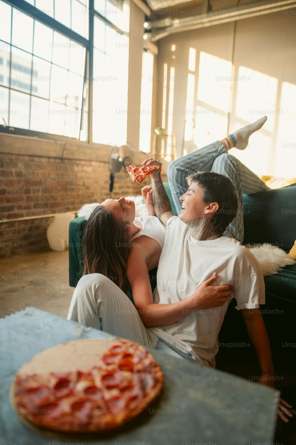 a man and a woman sitting on a couch eating pizza