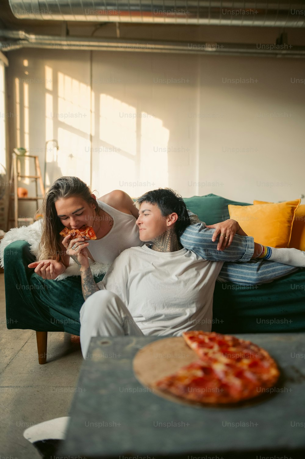 ソファに座ってピザを食べる男女
