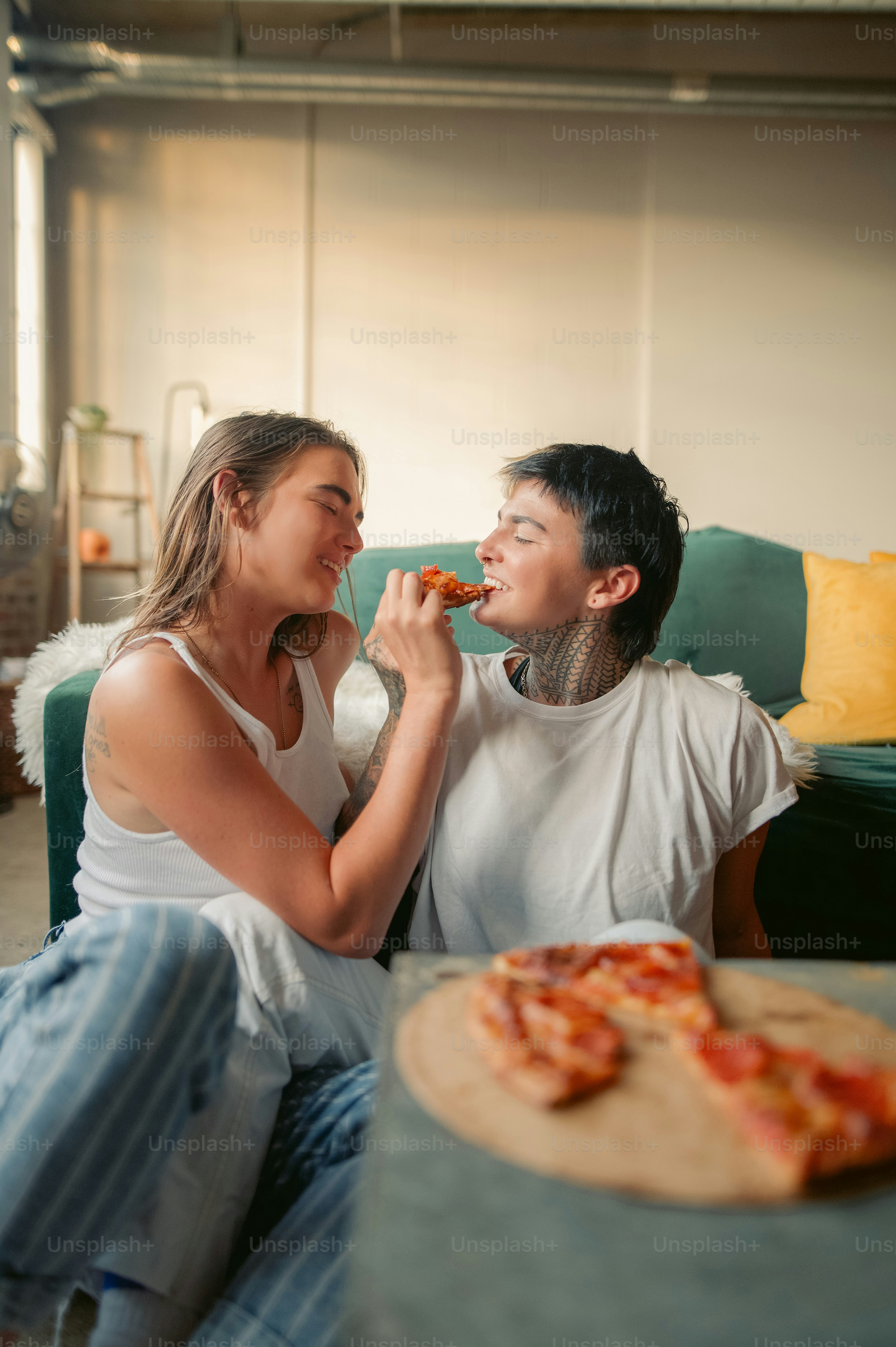 Un uomo e una donna seduti su un divano che mangiano pizza