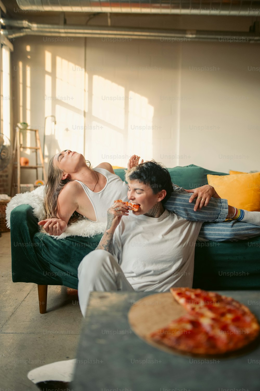 Ein Mann und eine Frau, die auf einer Couch liegen und Pizza essen
