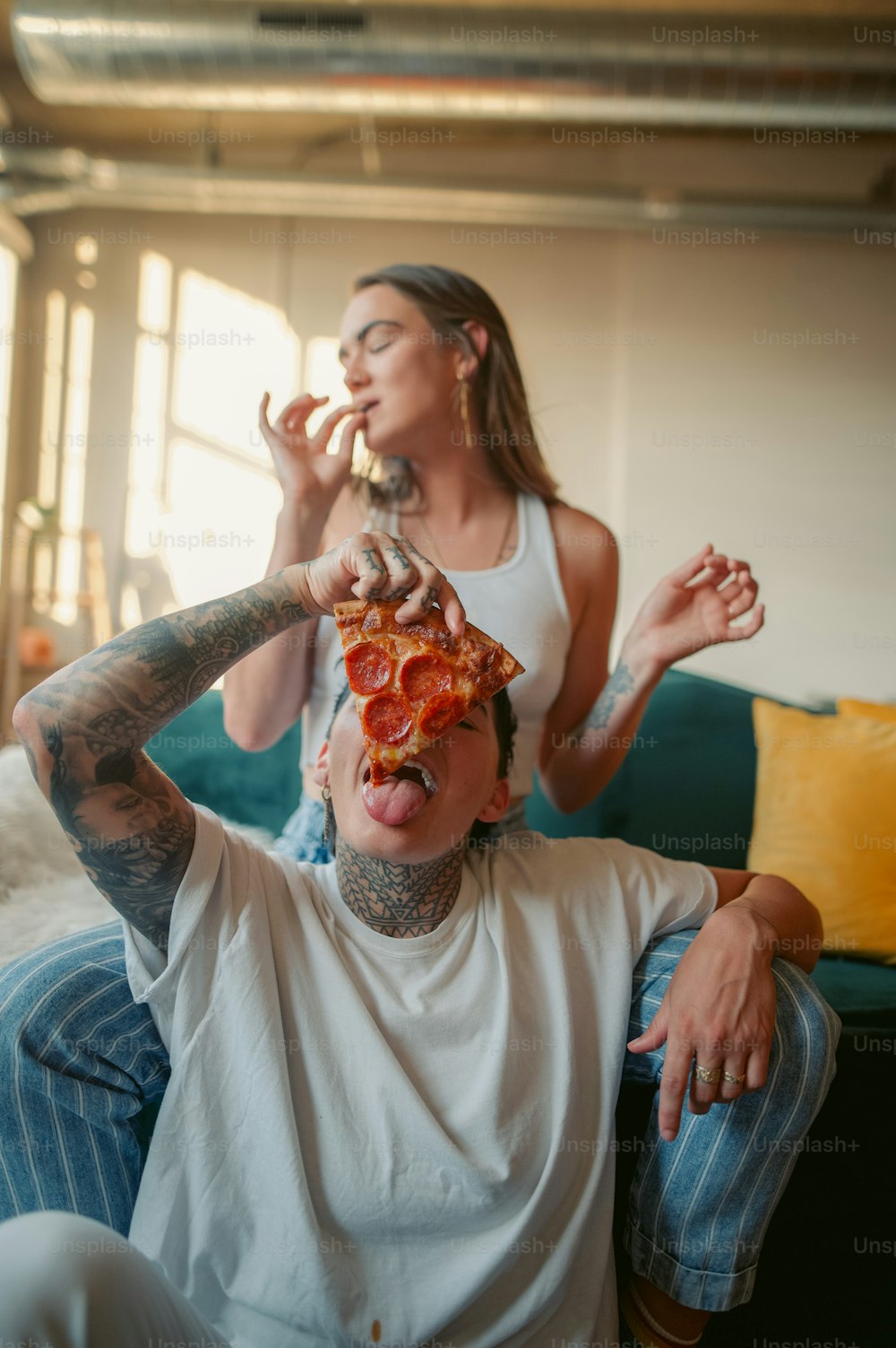 a woman sitting next to a man with a slice of pizza on his face