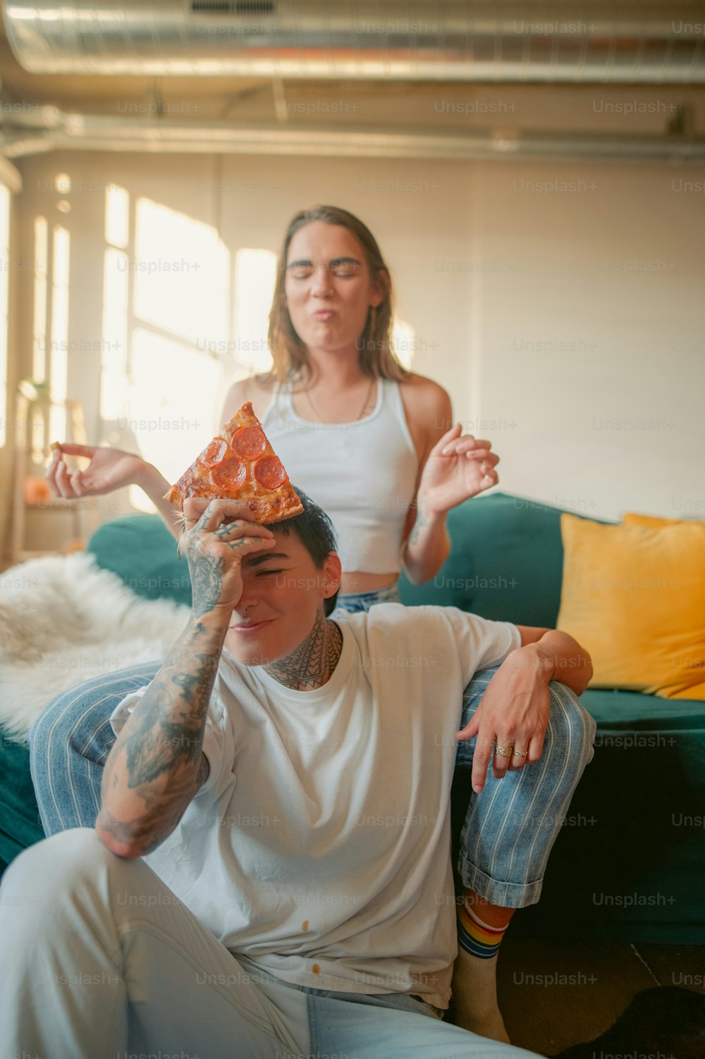 a woman sitting on a couch with a pizza on her head