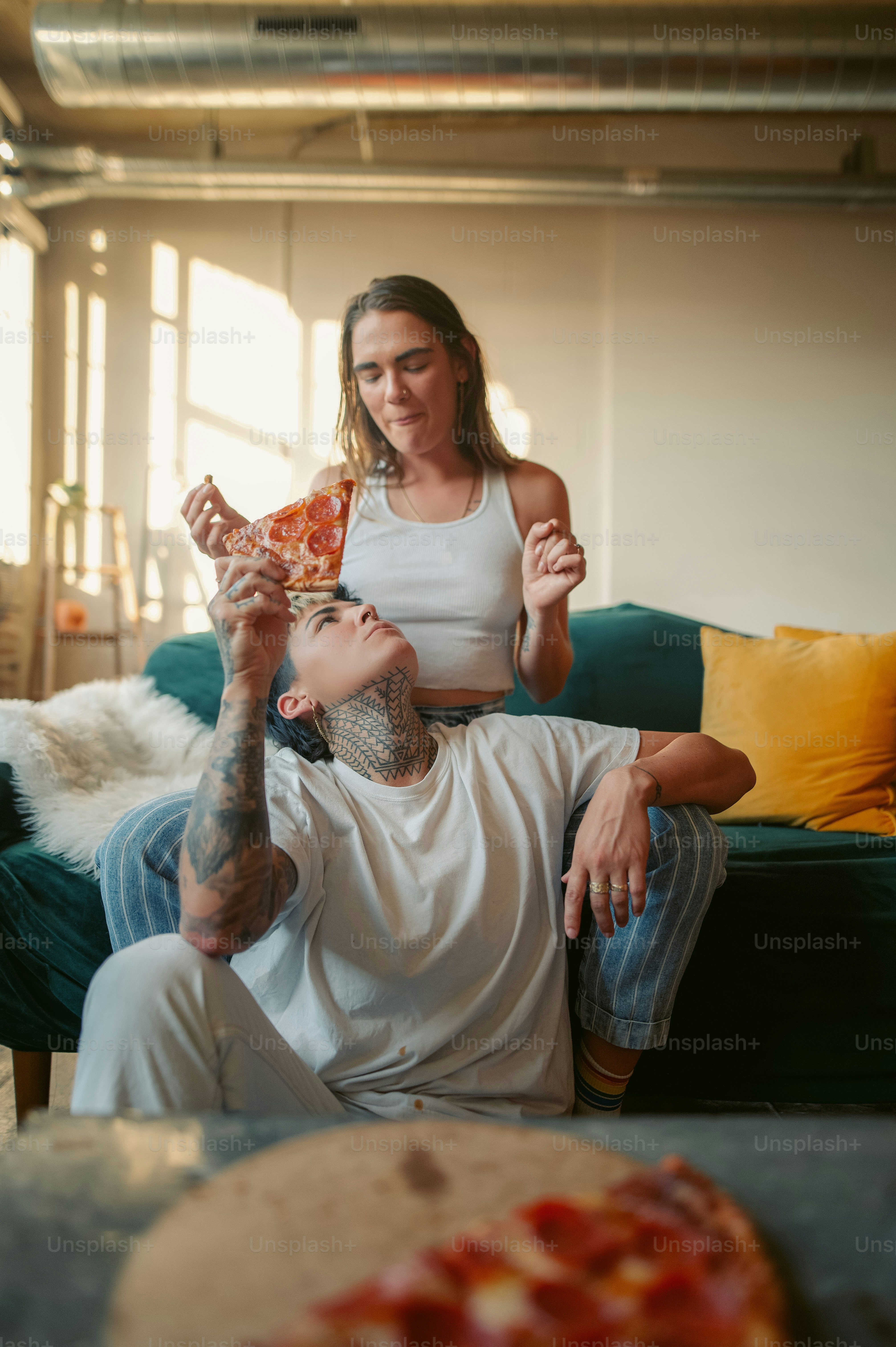 Un uomo e una donna seduti su un divano che mangiano pizza