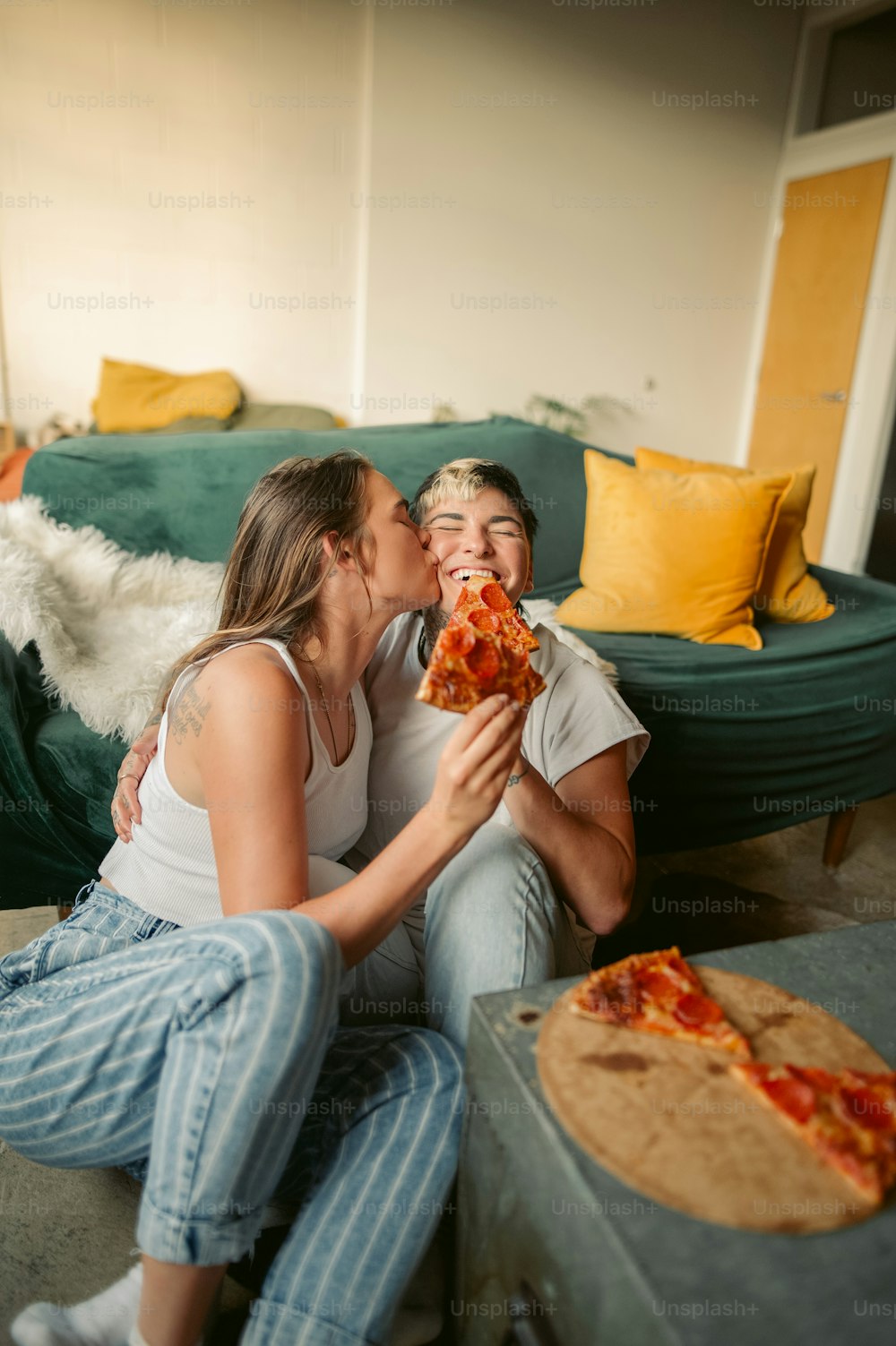 a man and woman sitting on the floor eating pizza