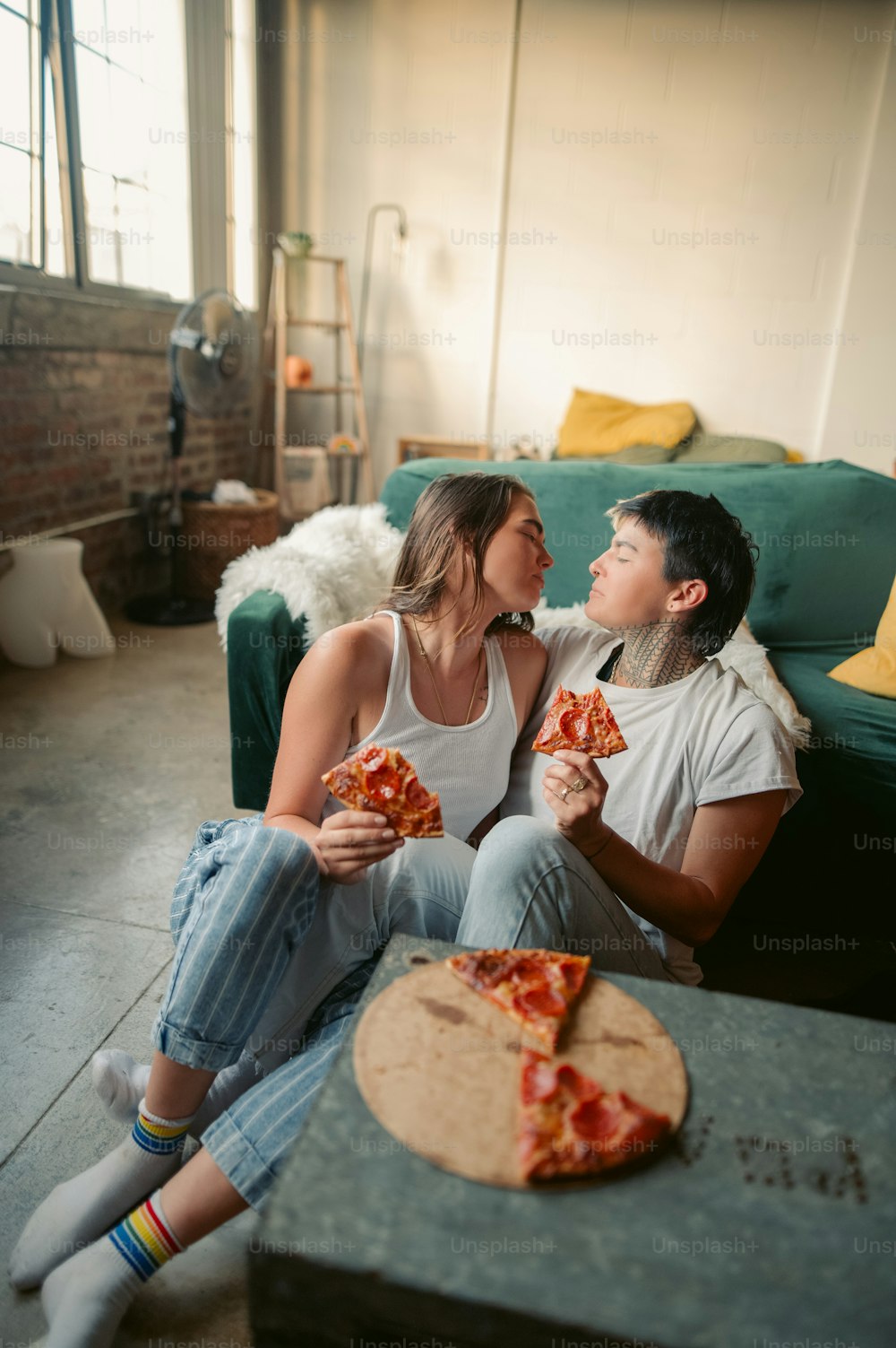 소파에 앉아 피자를 먹는 남자와 여자
