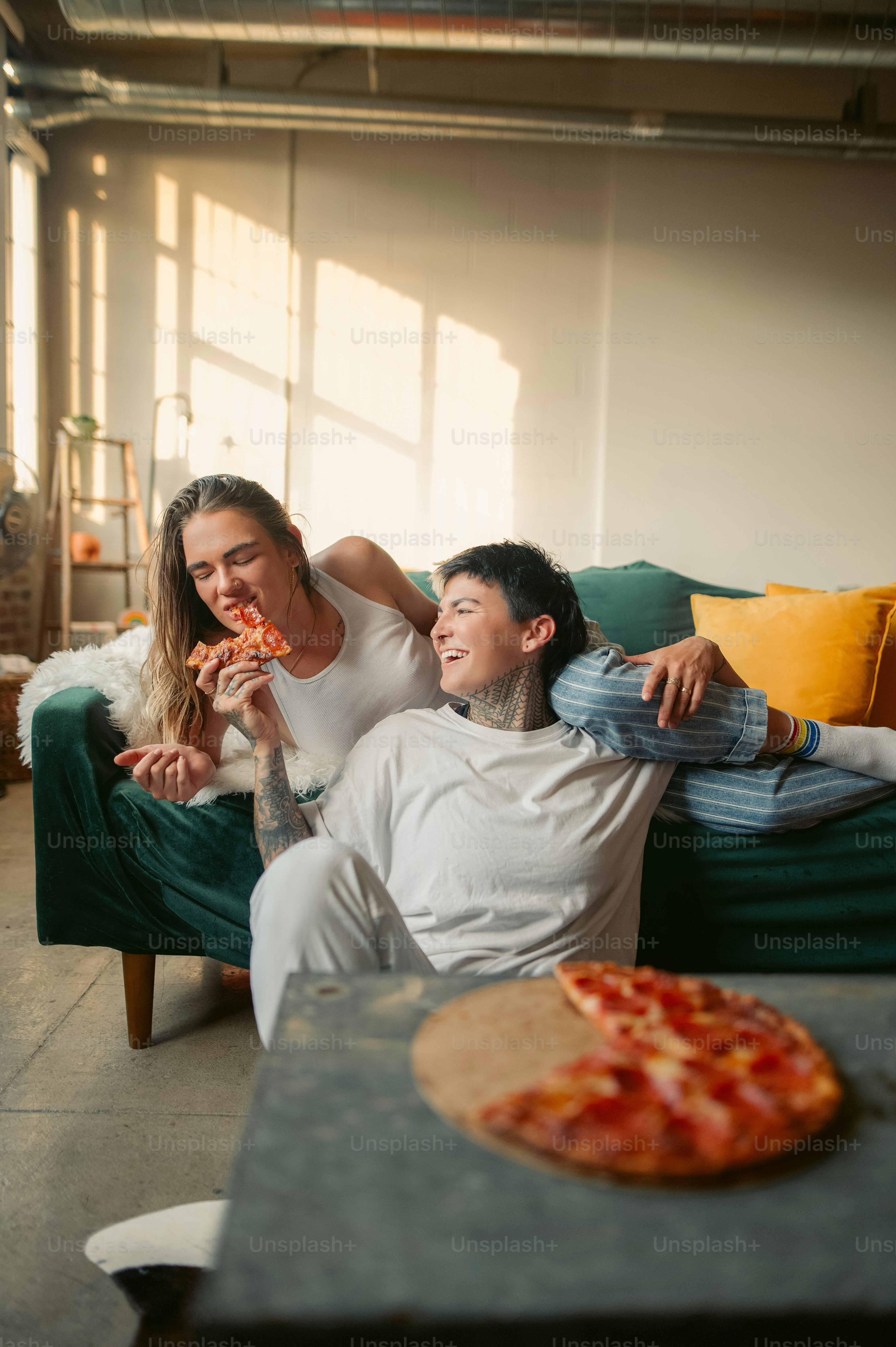 Un uomo e una donna seduti su un divano che mangiano pizza