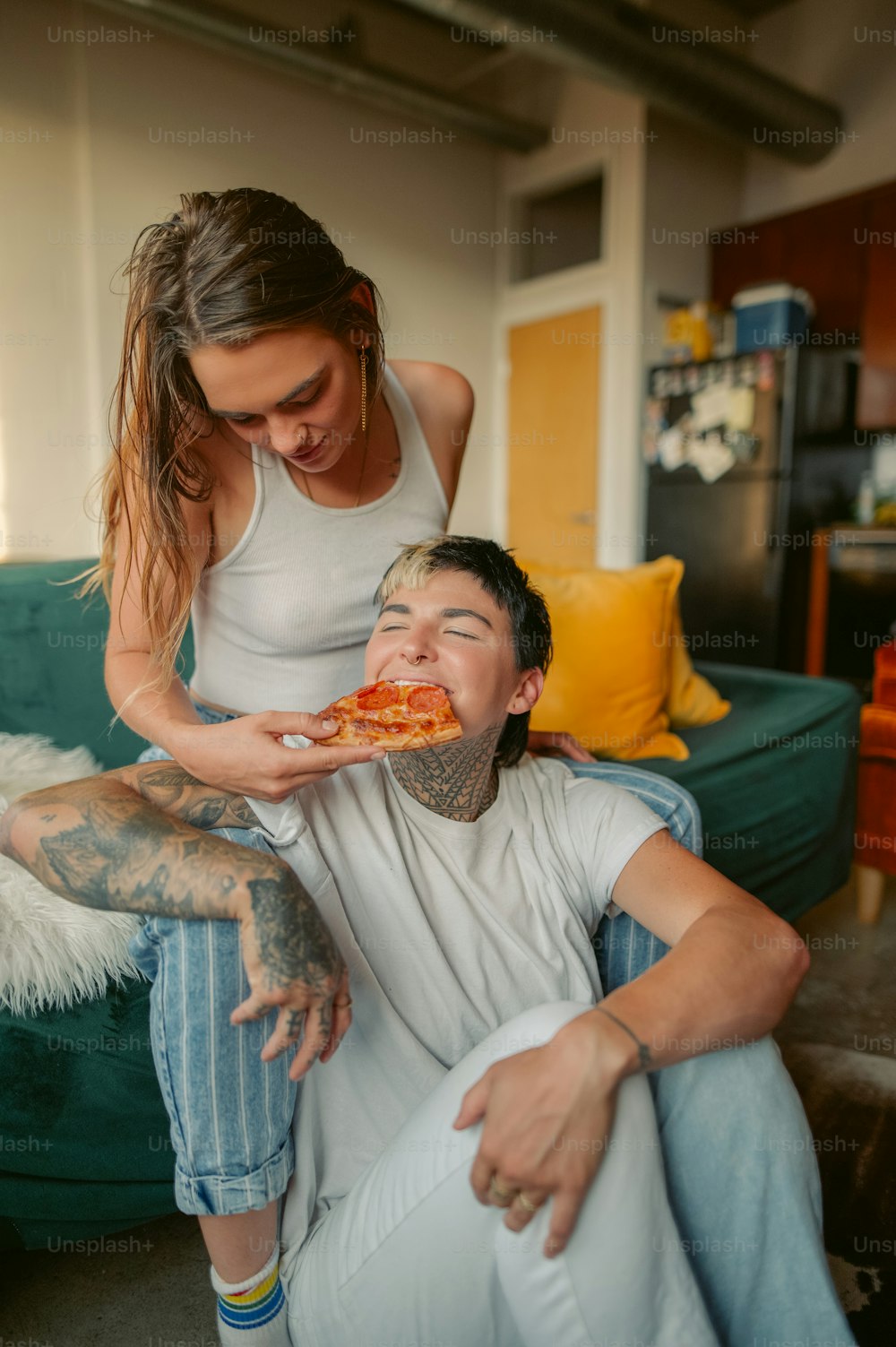 a woman is feeding a slice of pizza to a man