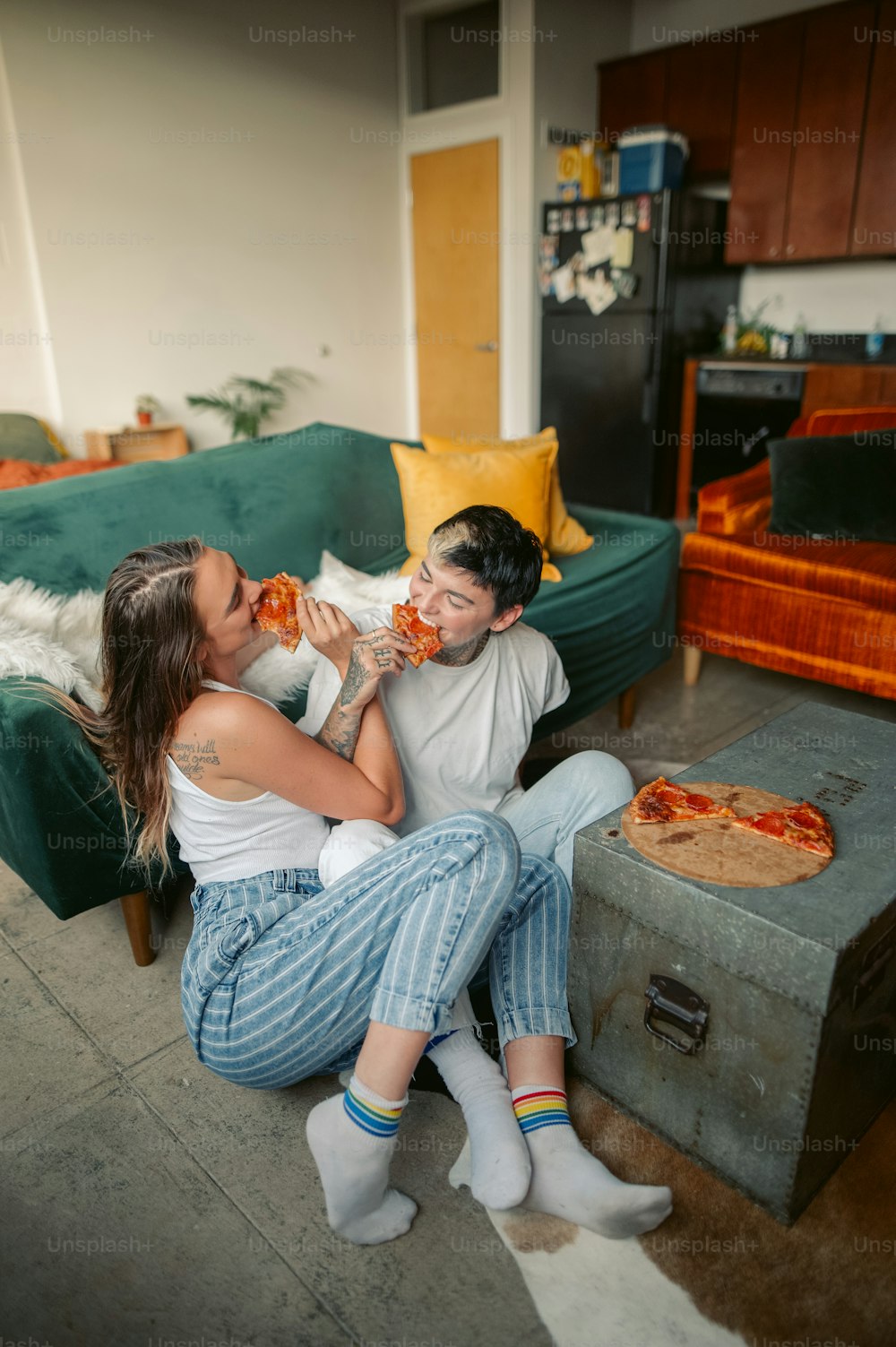 Un hombre y una mujer sentados en un sofá comiendo pizza