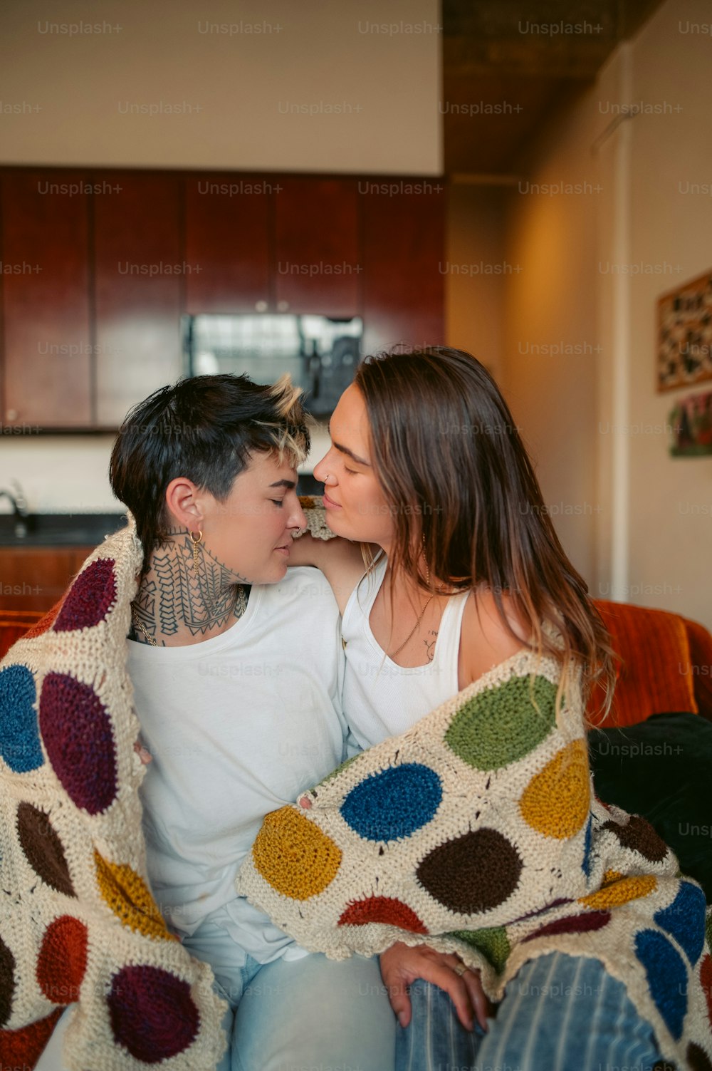 a man and woman sitting on a couch under a blanket