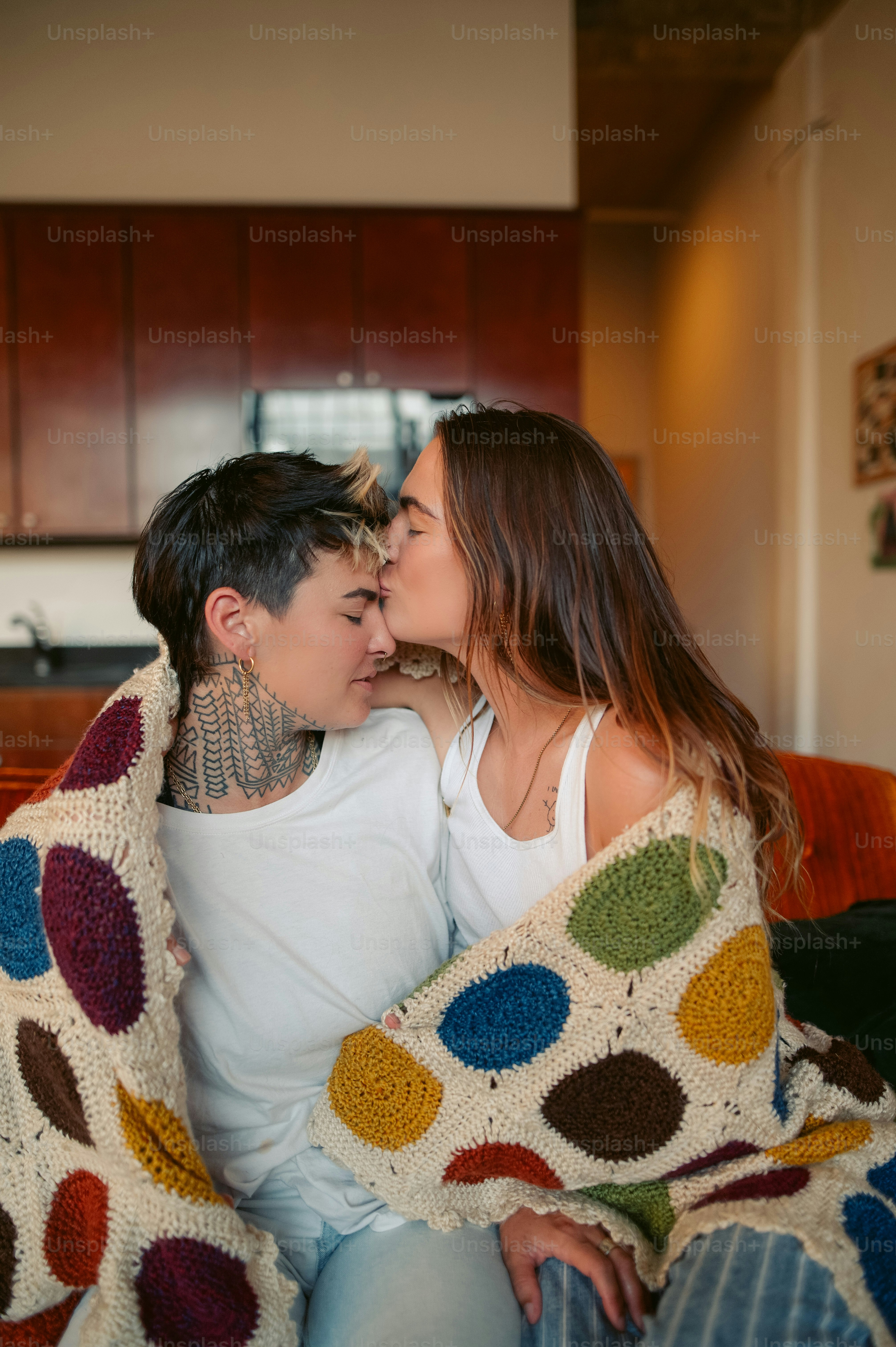 a man and woman sitting on a couch under a blanket