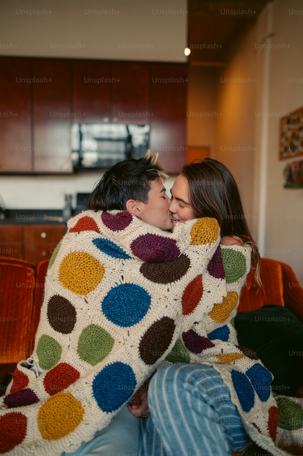 a man and a woman cuddle under a crocheted blanket