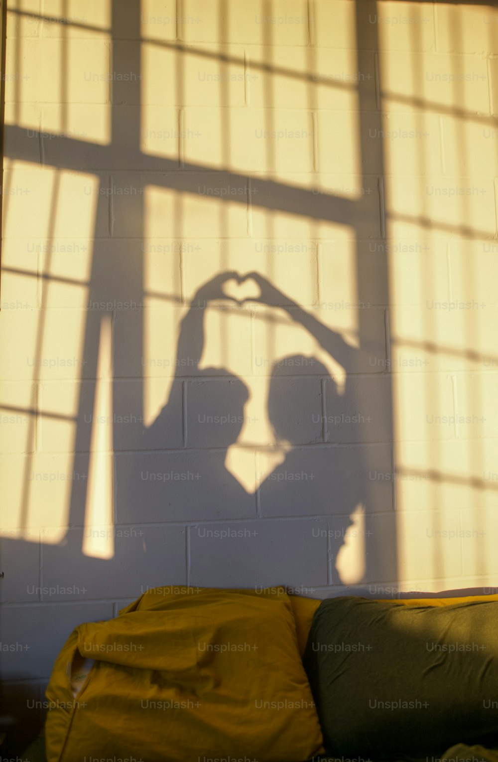 a shadow of a person making a heart with their hands
