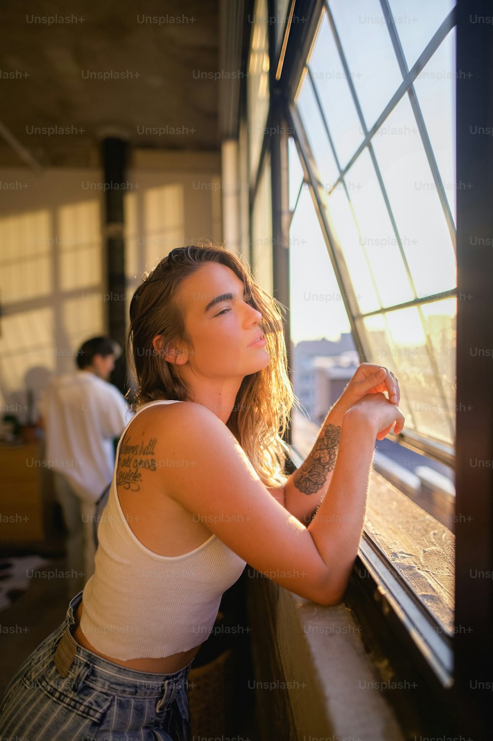 a woman leaning against a window looking out at the city