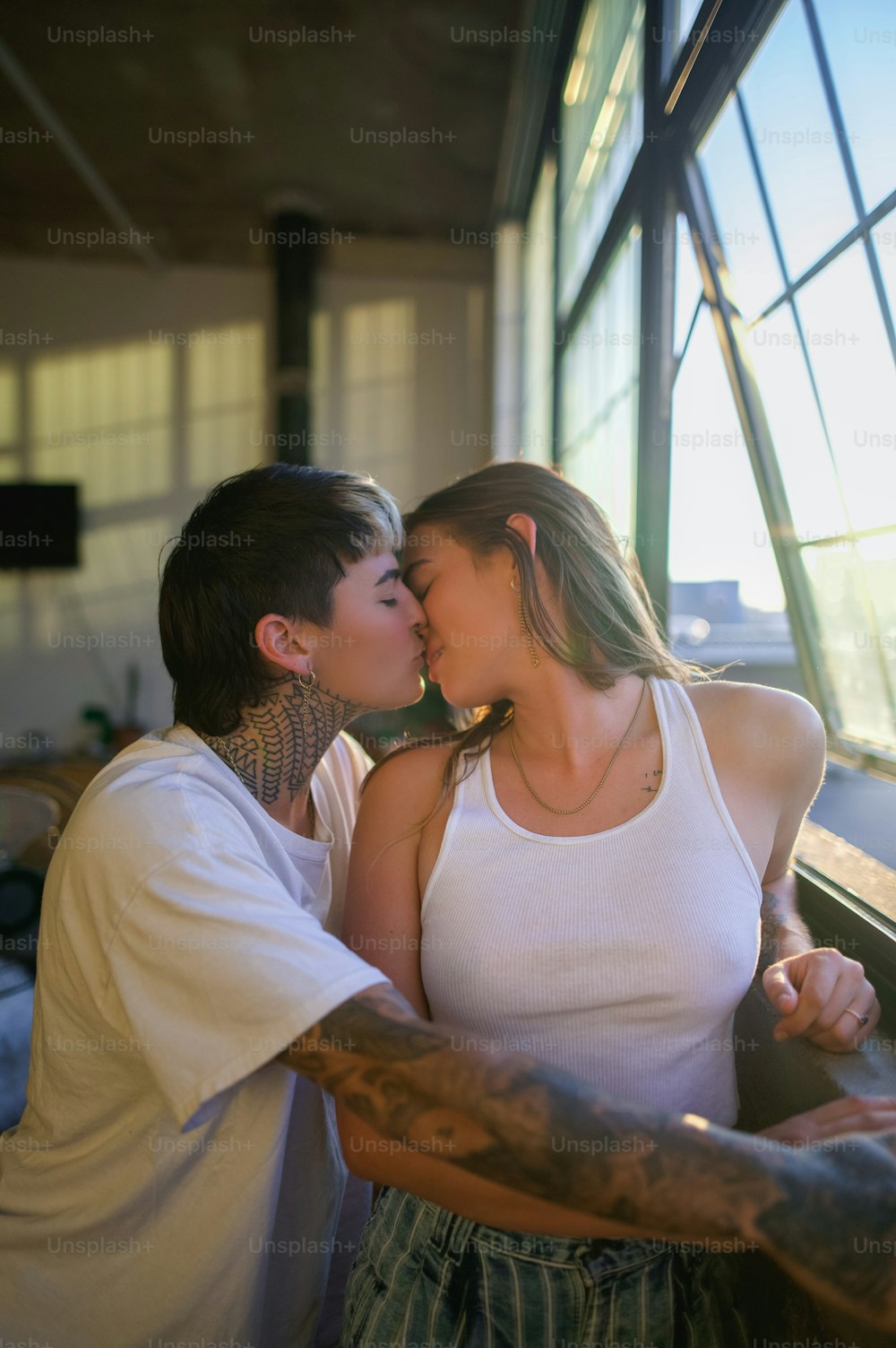 a man and woman kissing each other in front of a window