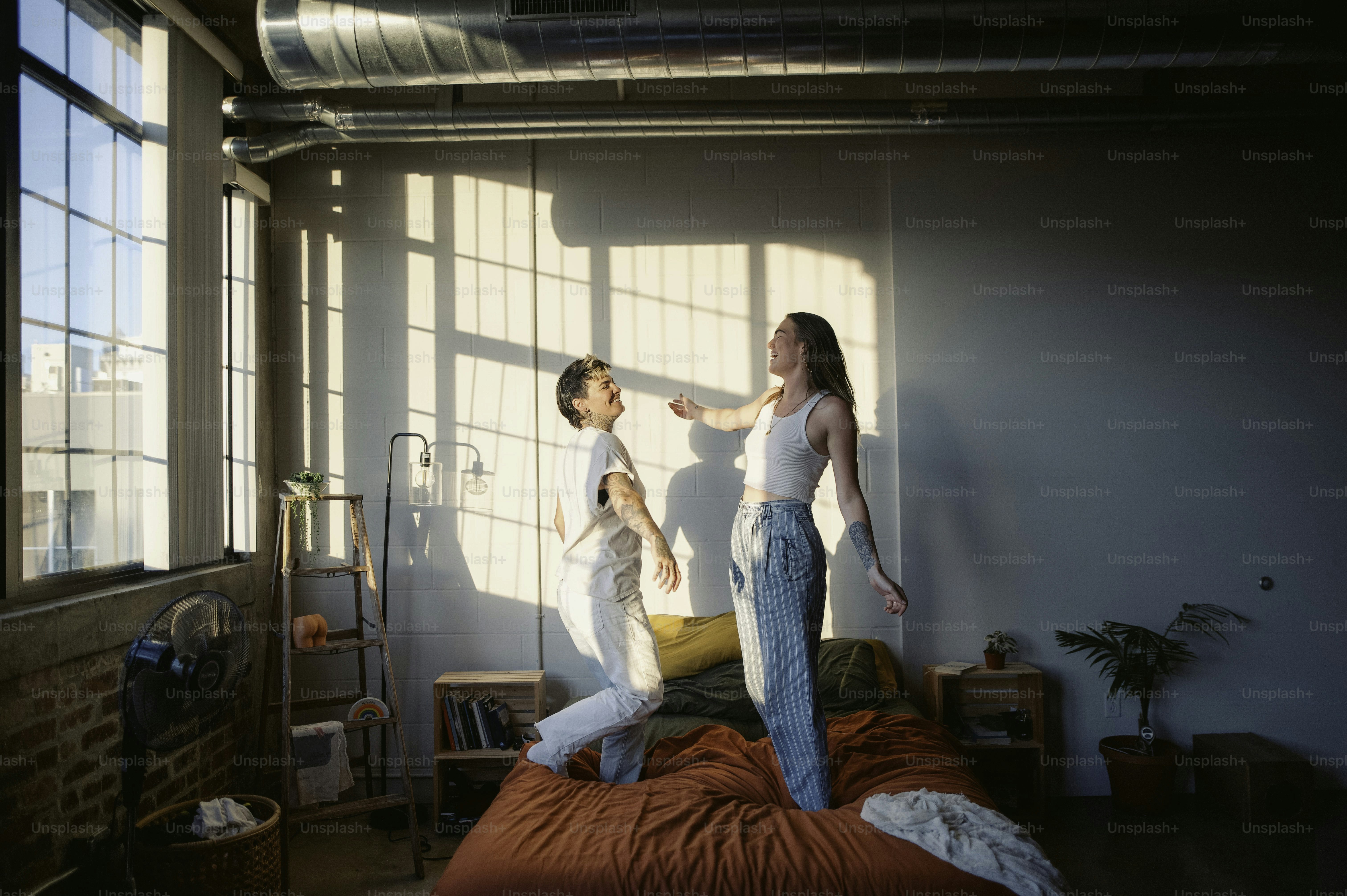 um homem e uma mulher em pé sobre uma cama