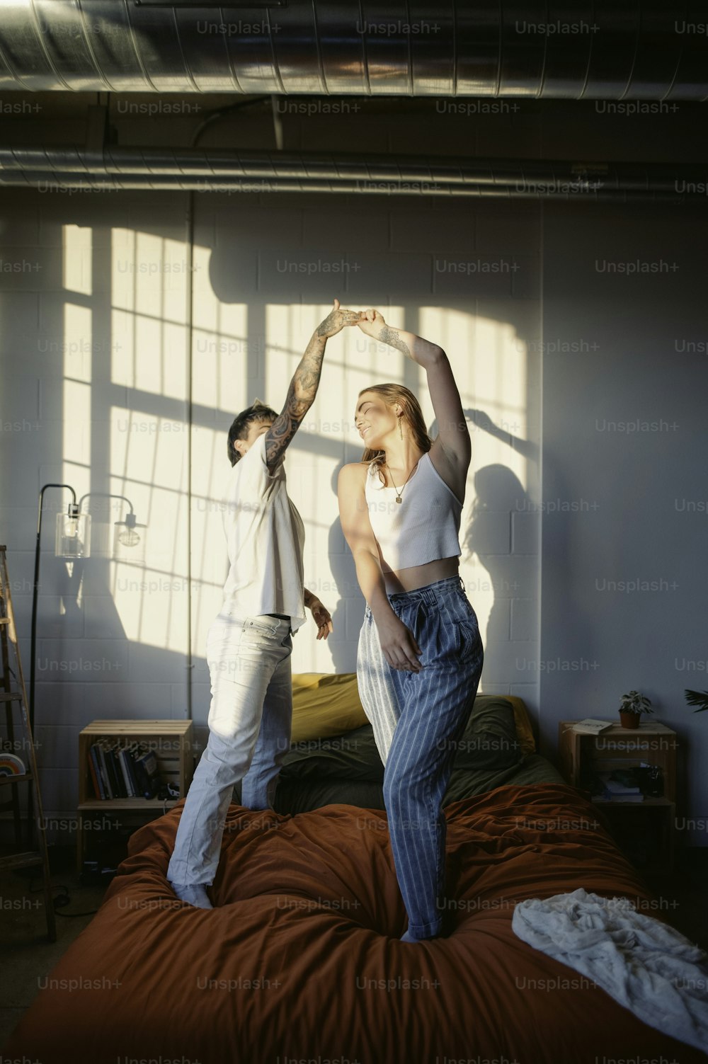 a man and a woman standing on top of a bed