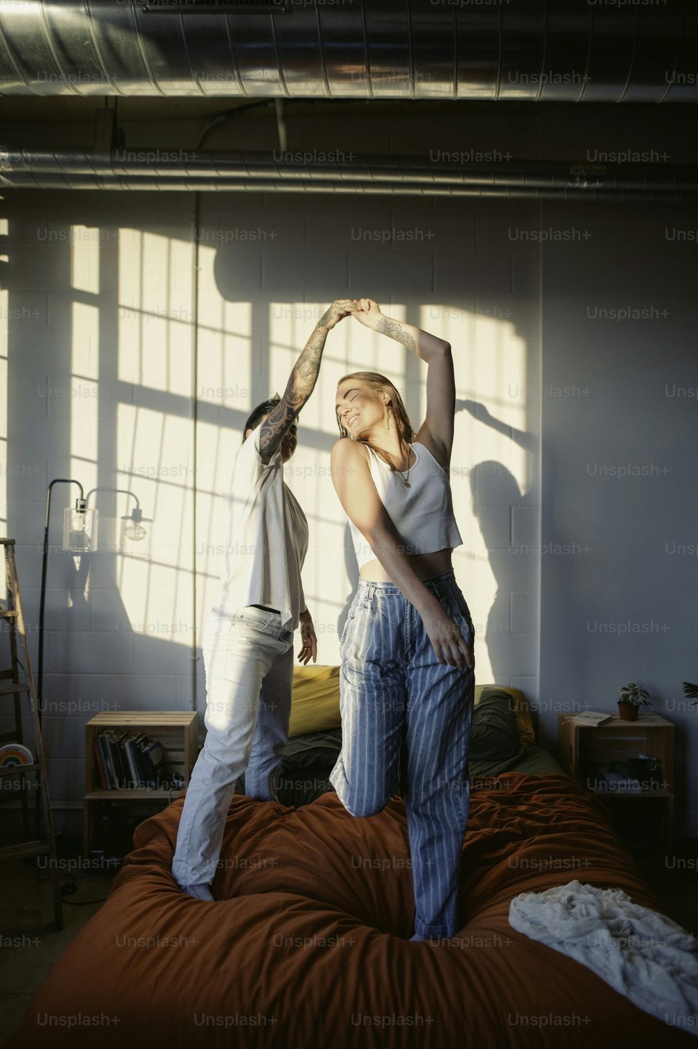 a woman standing on top of a bed next to a man