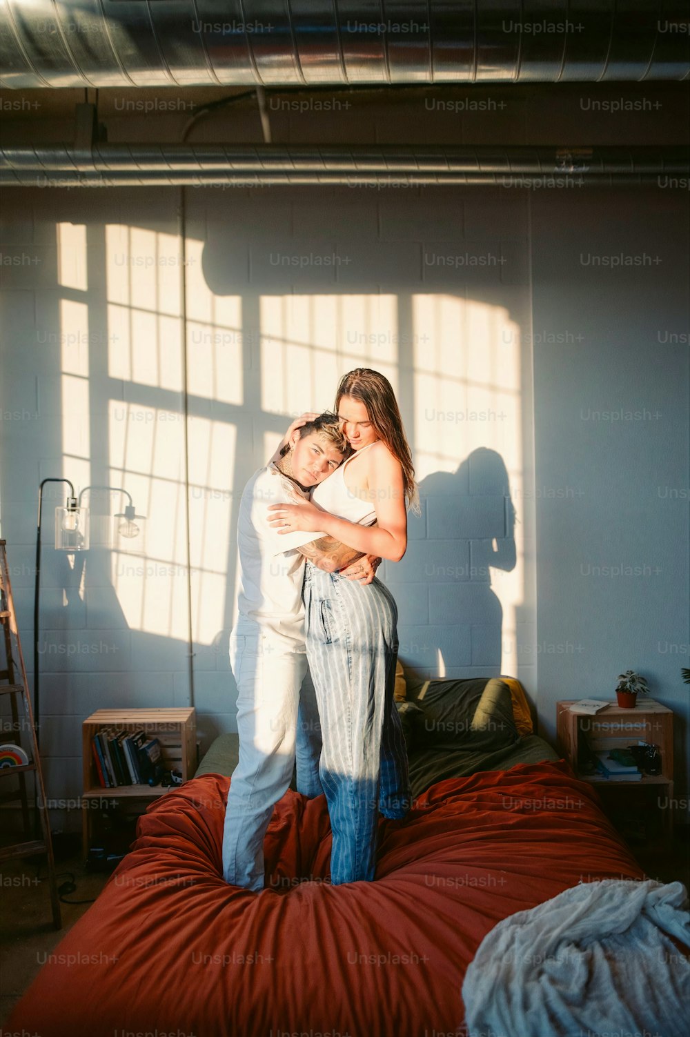 a man holding a woman in his arms while standing on a bed