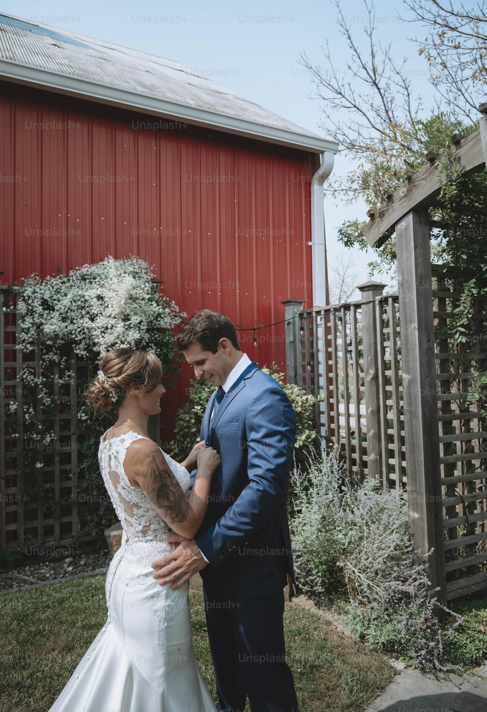 a bride and groom standing in front of a red barn
