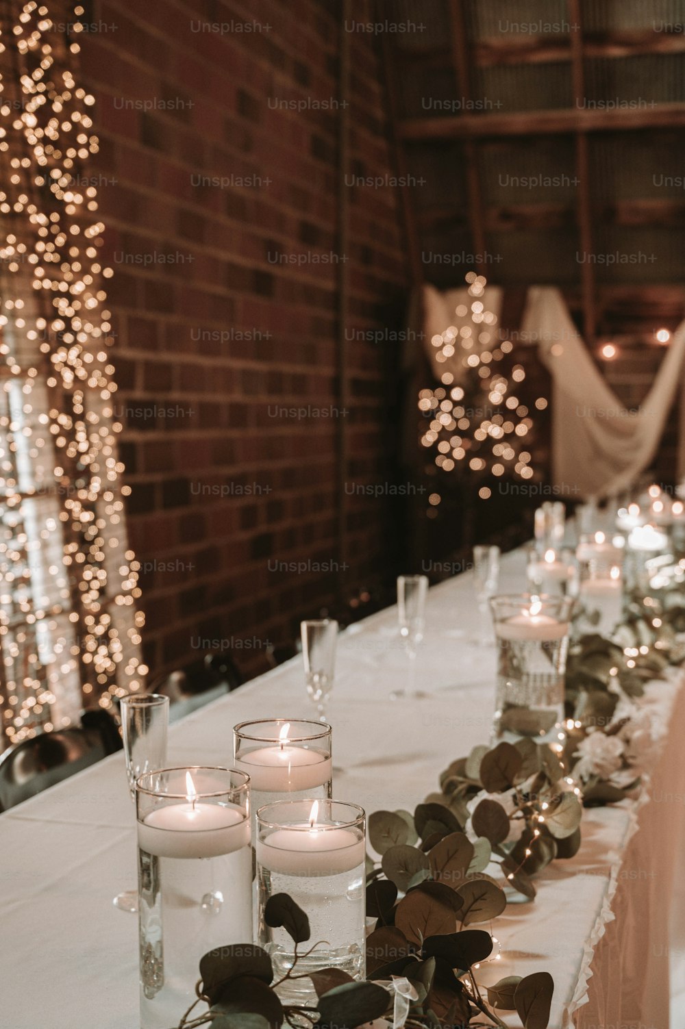Una mesa larga con velas y vegetación