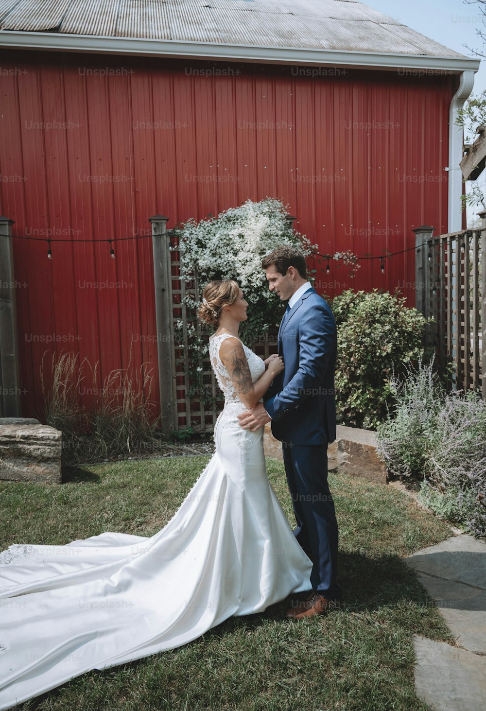 a bride and groom standing in front of a red barn