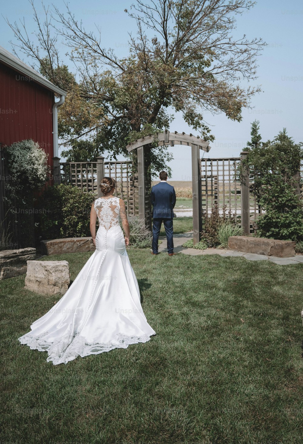 a bride and groom walking away from the barn