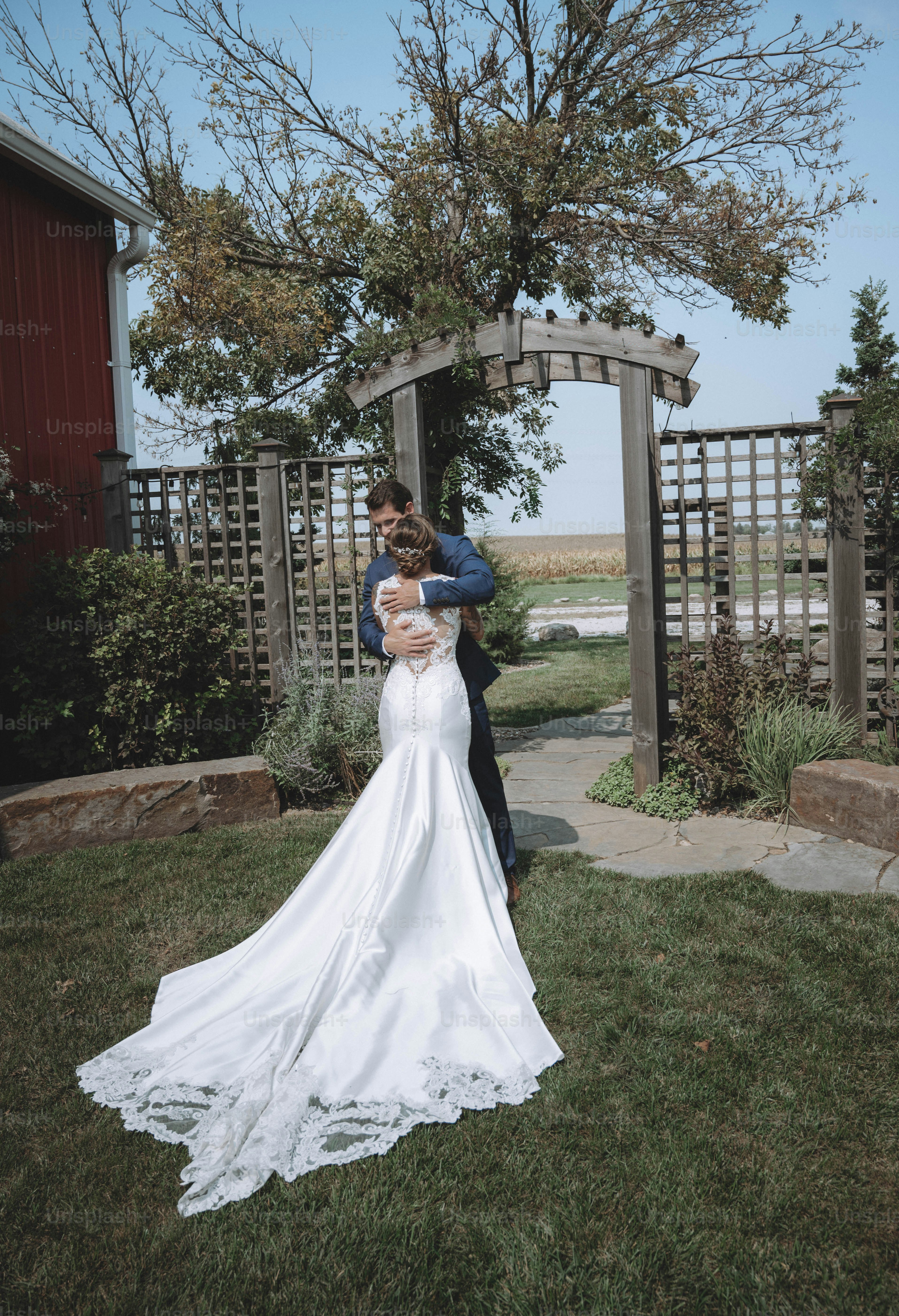 a bride and groom standing in front of a wooden arbor