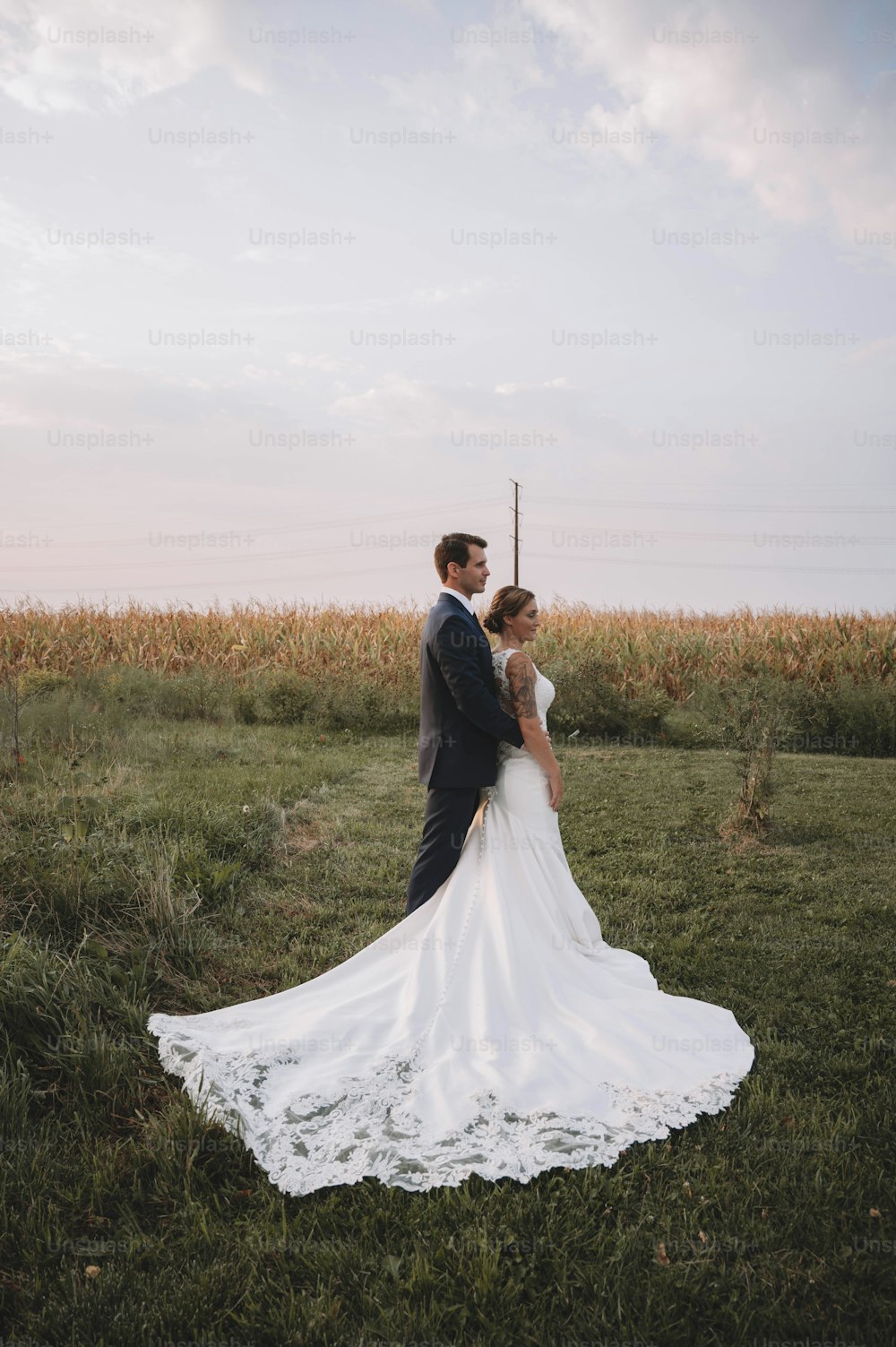 a bride and groom standing in a field