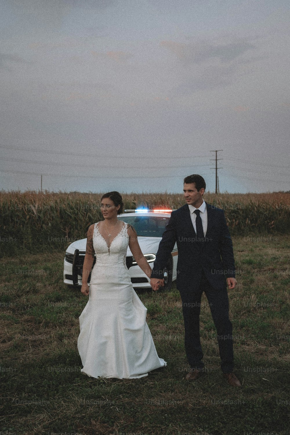 Braut und Bräutigam Händchen haltend vor einem Polizeiauto