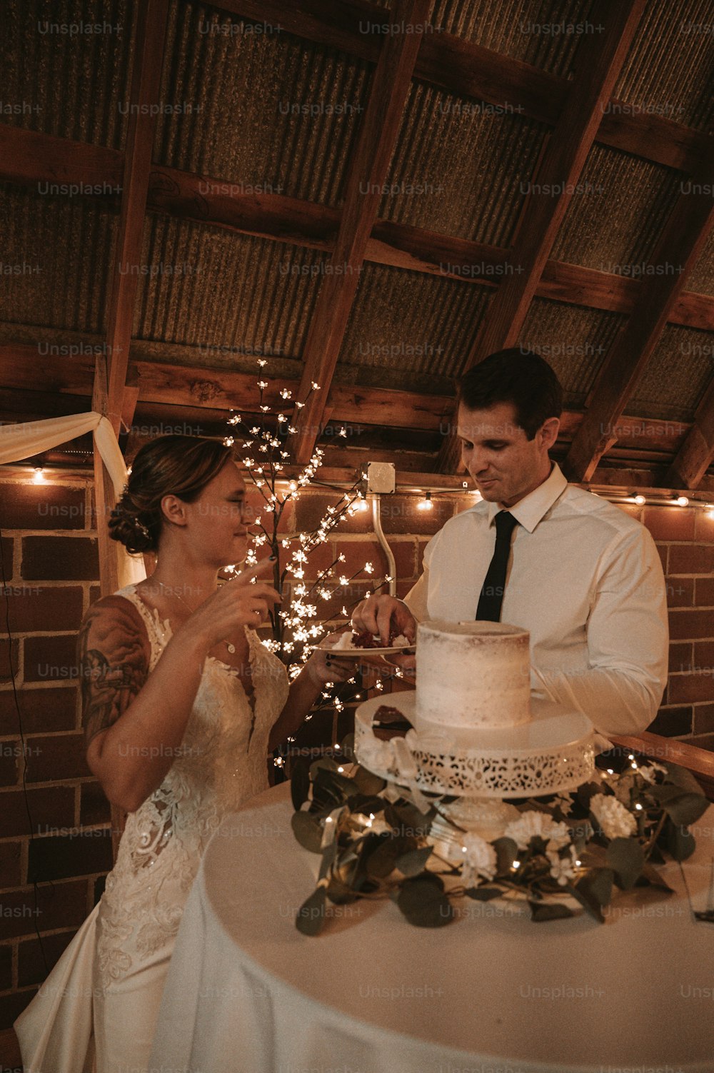 um homem e uma mulher em pé na frente de um bolo