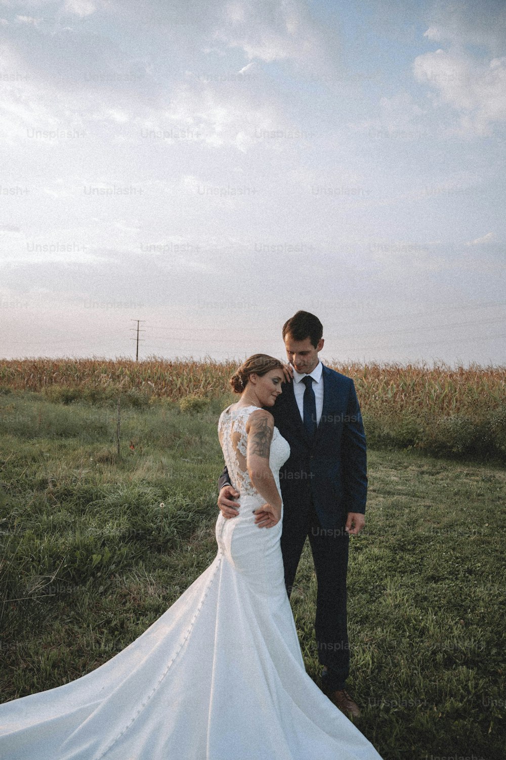 a bride and groom standing in a field