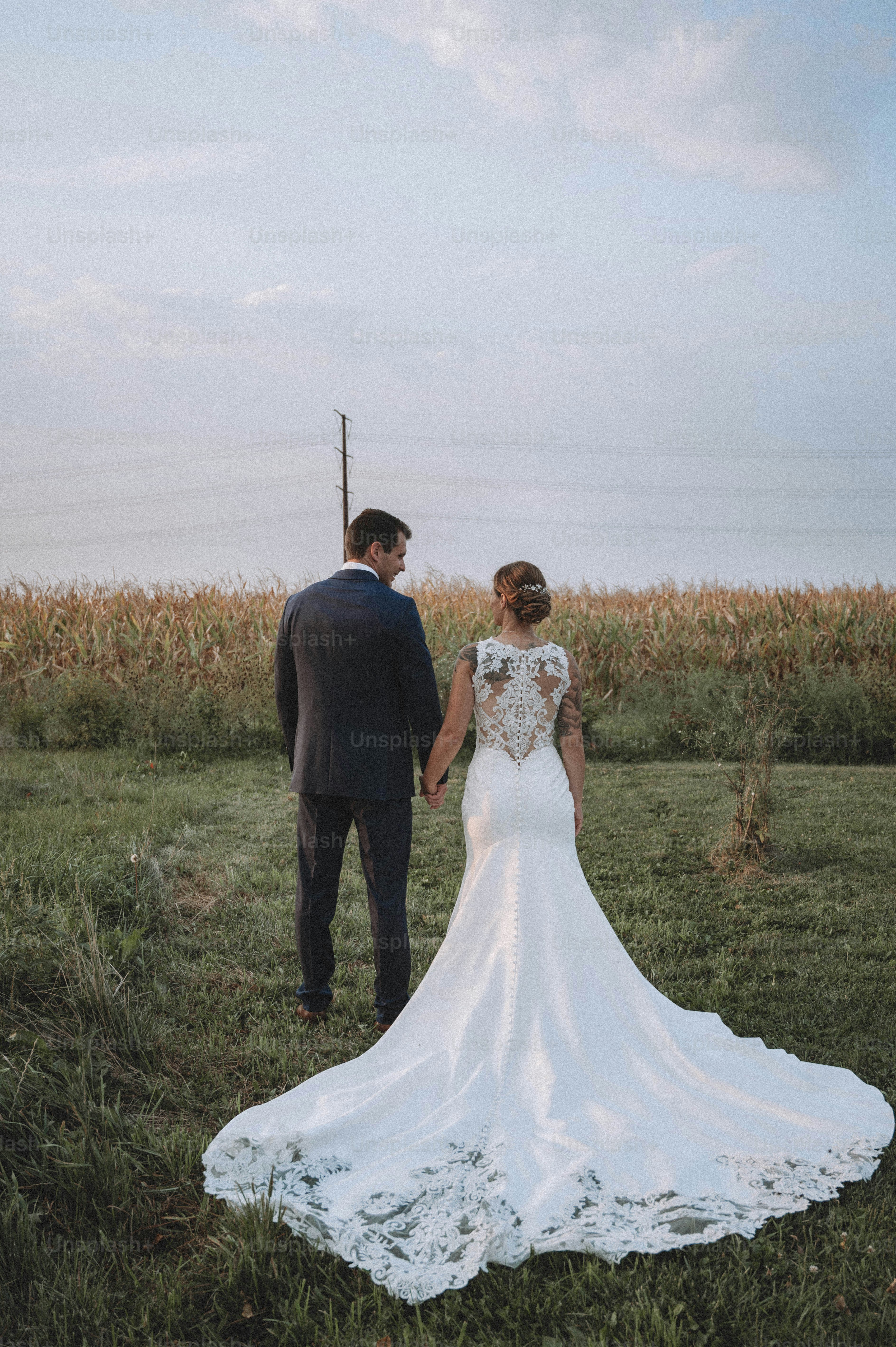 a bride and groom holding hands in a field