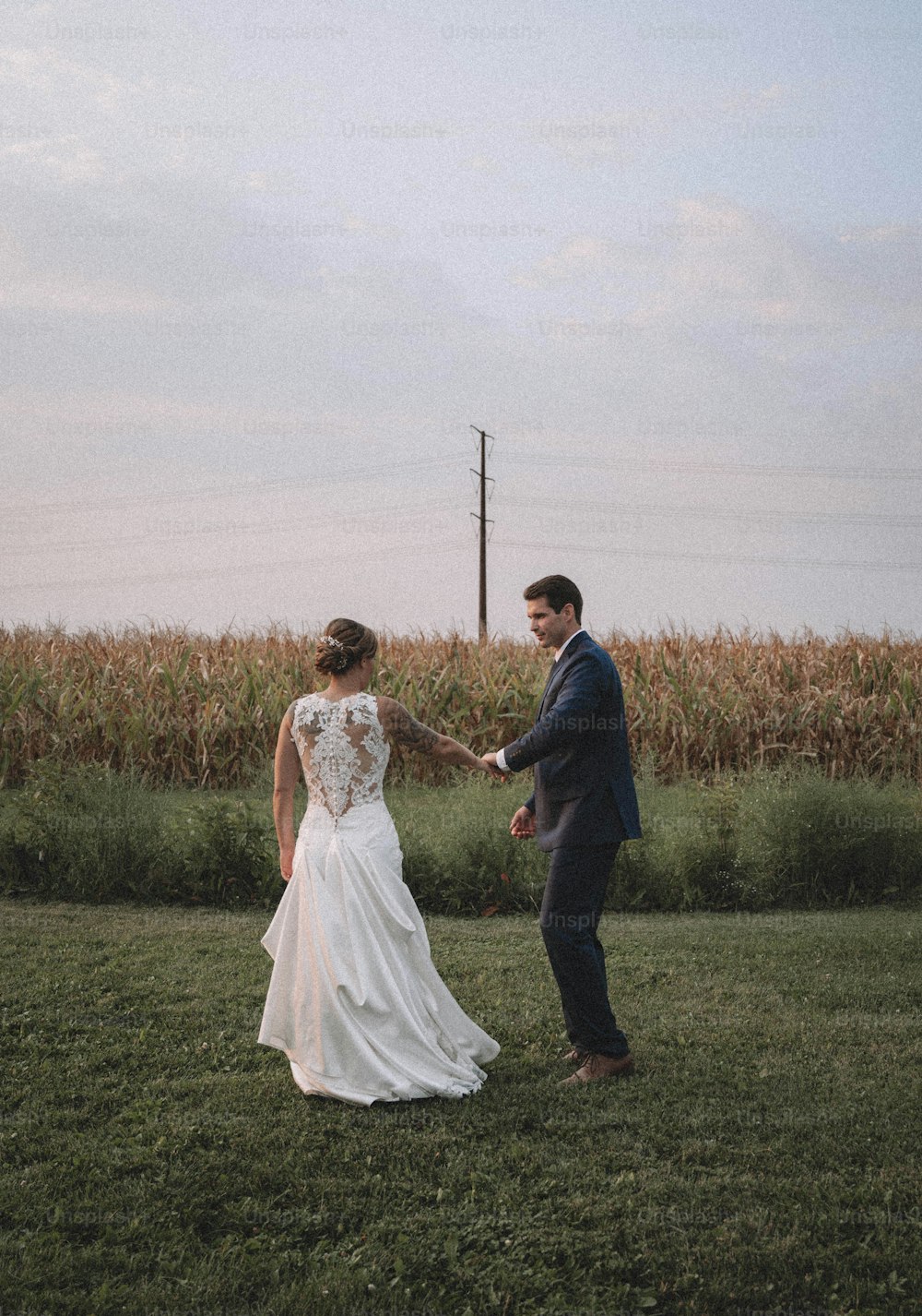 a bride and groom holding hands in a field