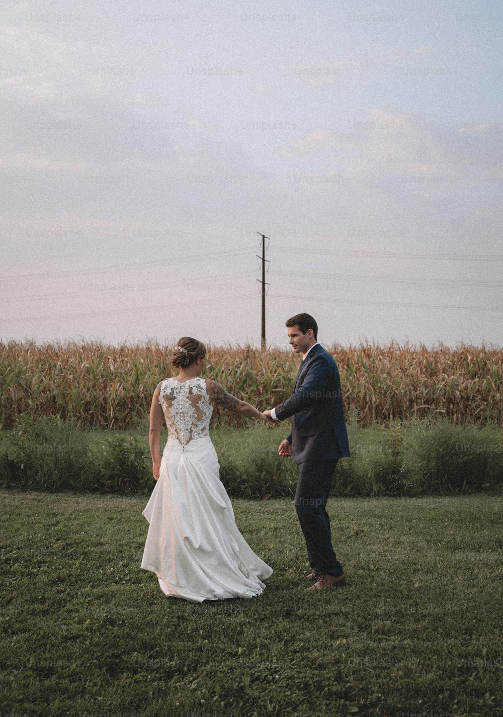 Braut und Bräutigam, Händchen haltend auf einem Feld