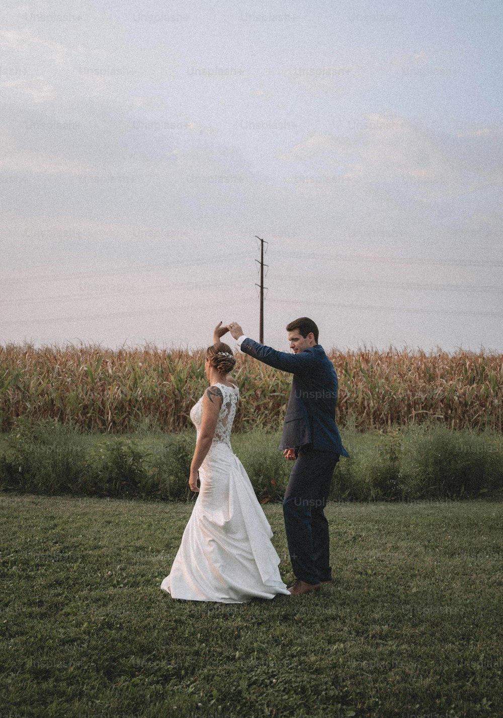 a bride and groom dancing in a field