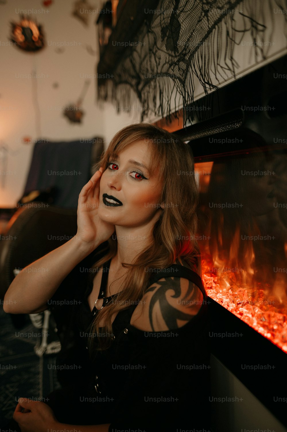 a woman with black makeup is posing in front of a fire