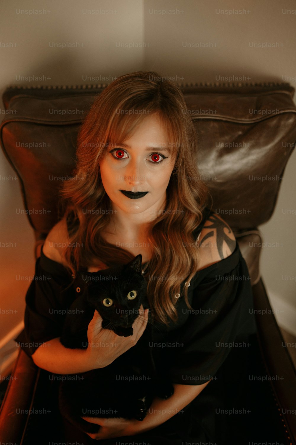 Eine Frau in einem schwarzen Kleid, die eine schwarze Katze hält