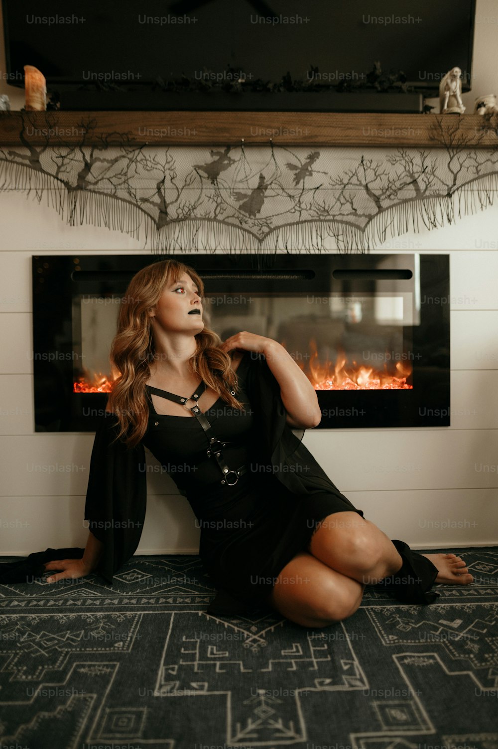a woman sitting on the floor in front of a fireplace