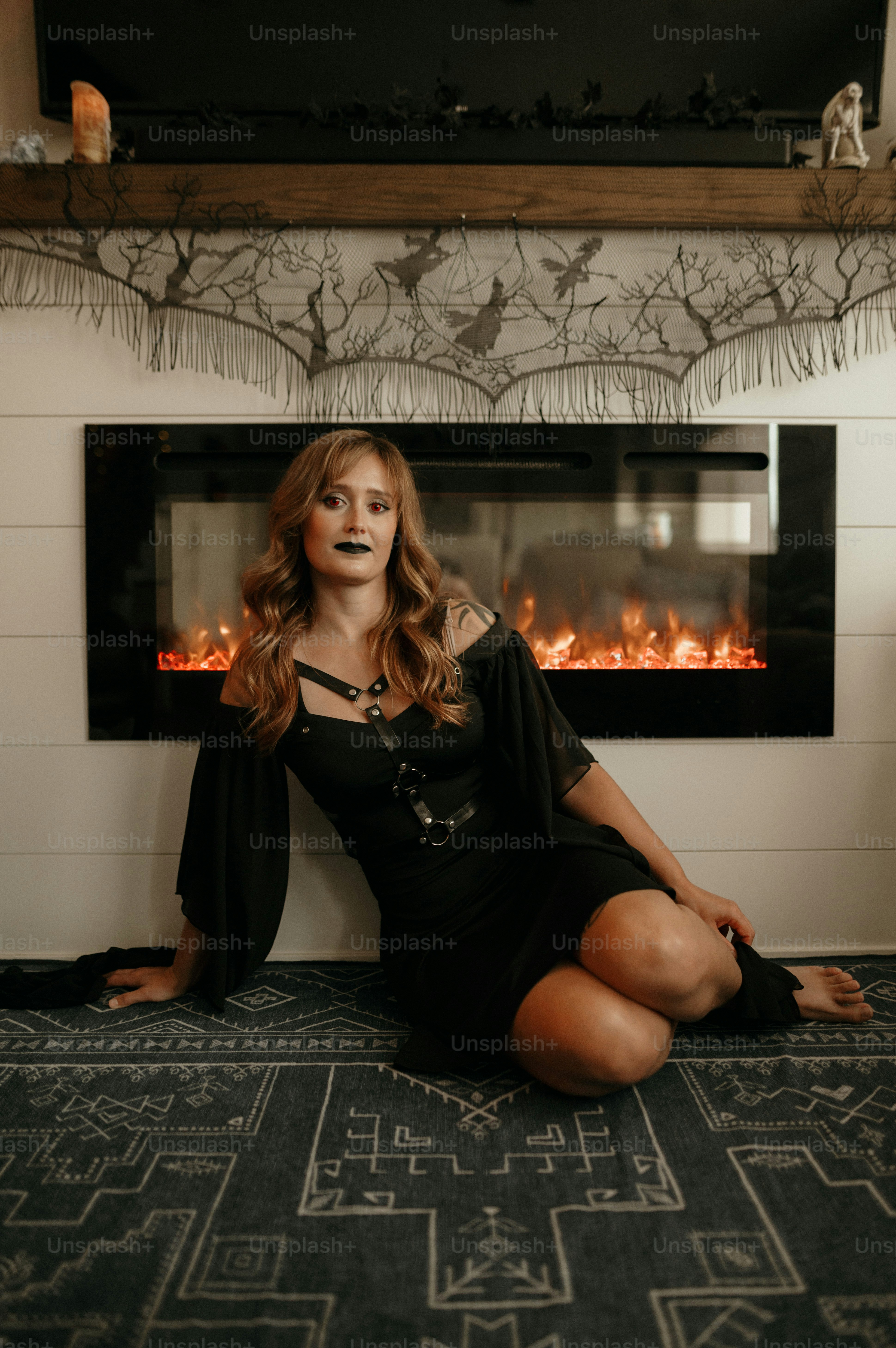 a woman sitting on the floor in front of a fireplace