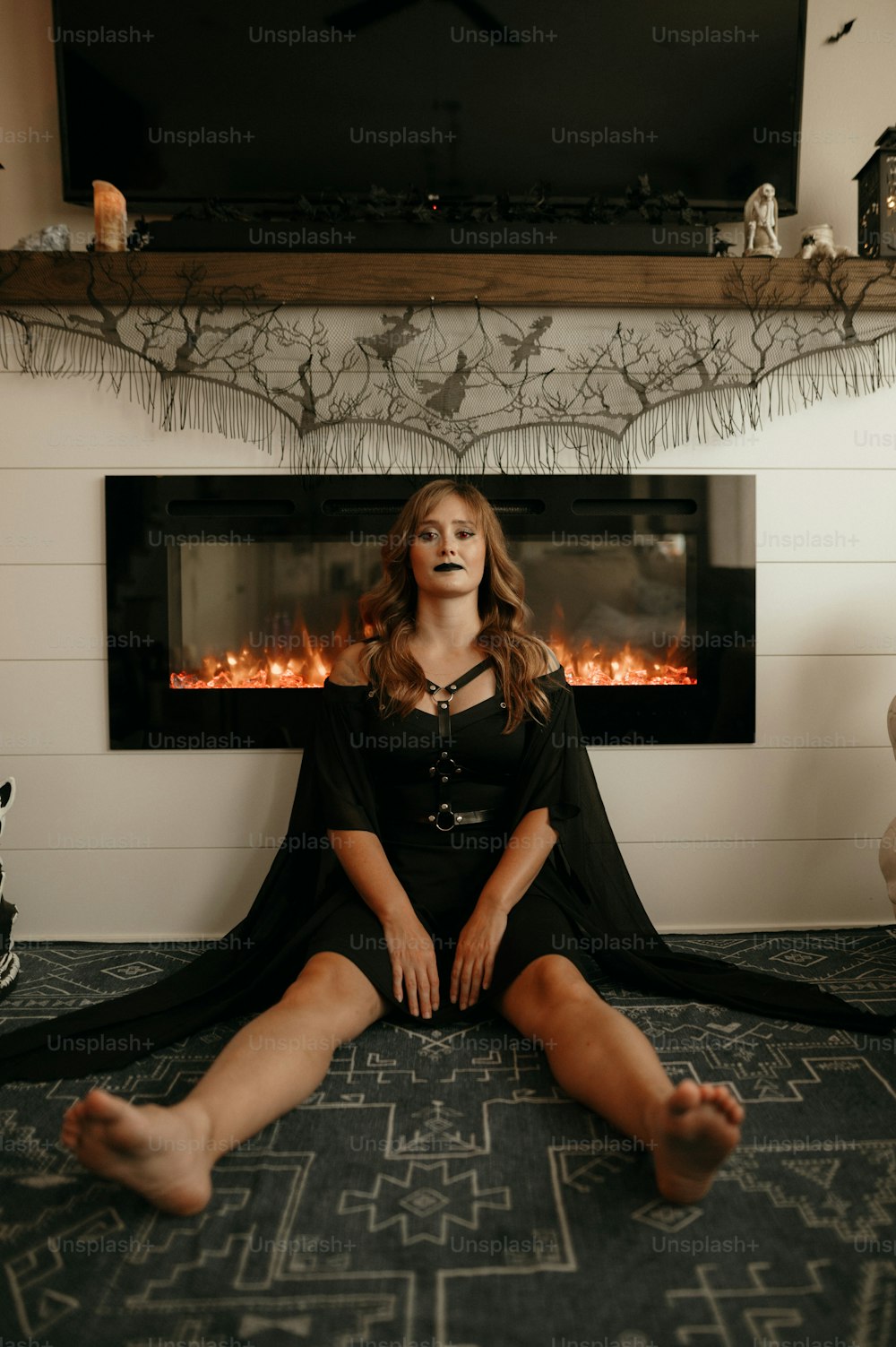 a woman sitting on the floor in front of a fireplace