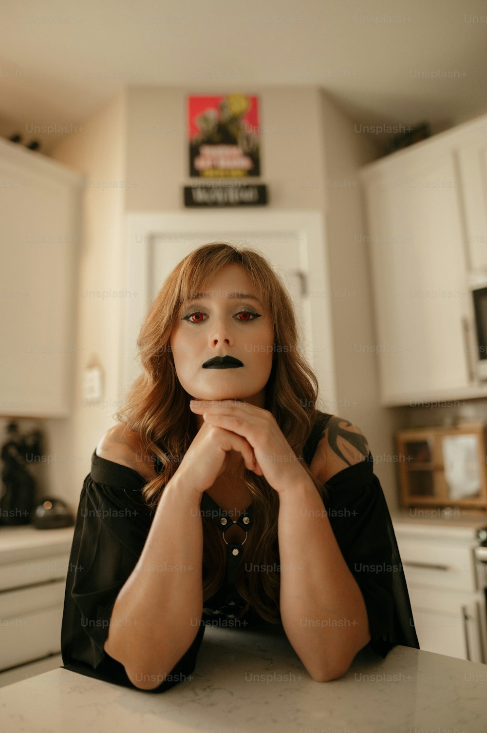 a woman sitting at a kitchen counter with her hands on her face